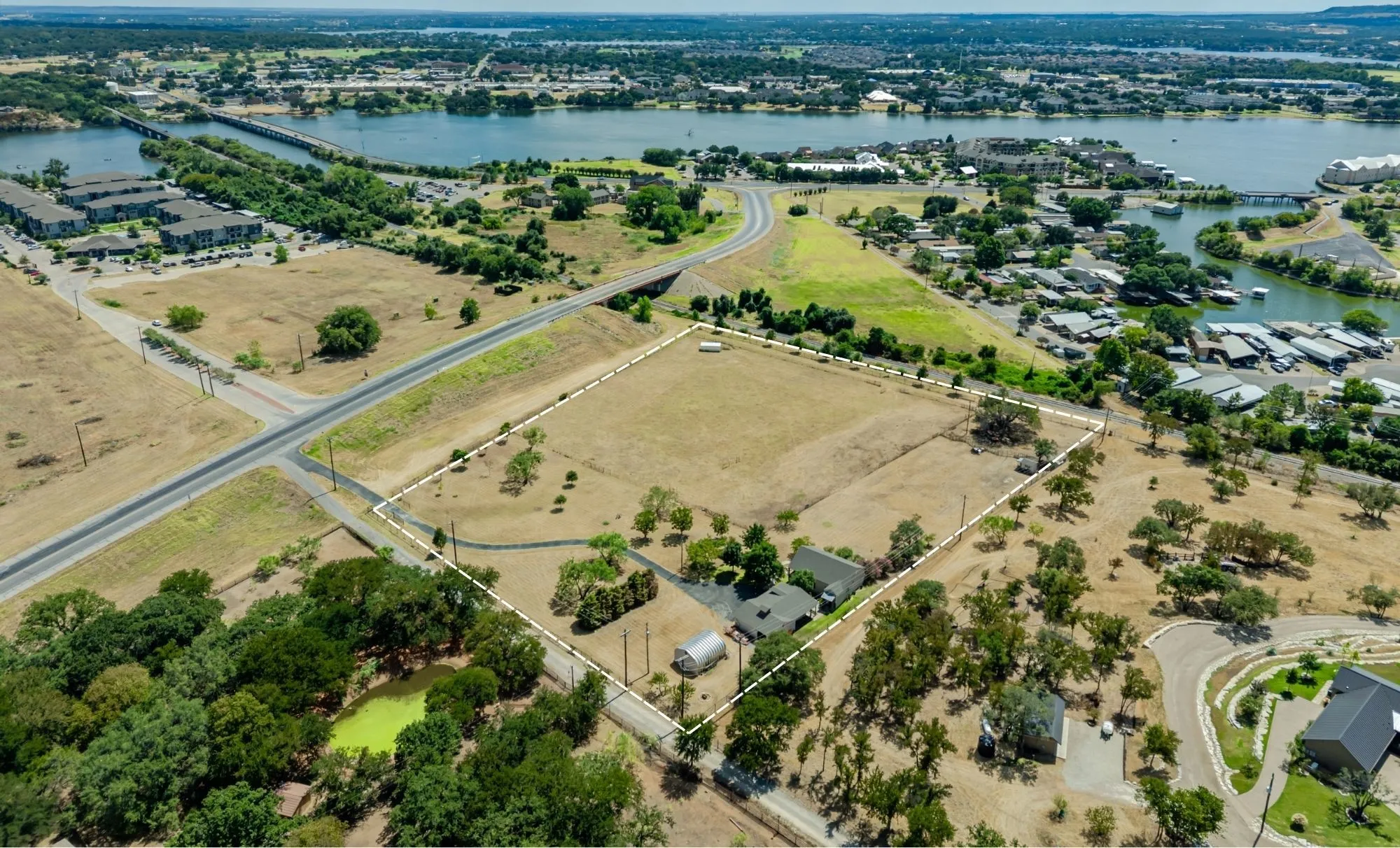 Expansive lot featuring a primary residence, a detached secondary structure, mature trees, and direct road frontage