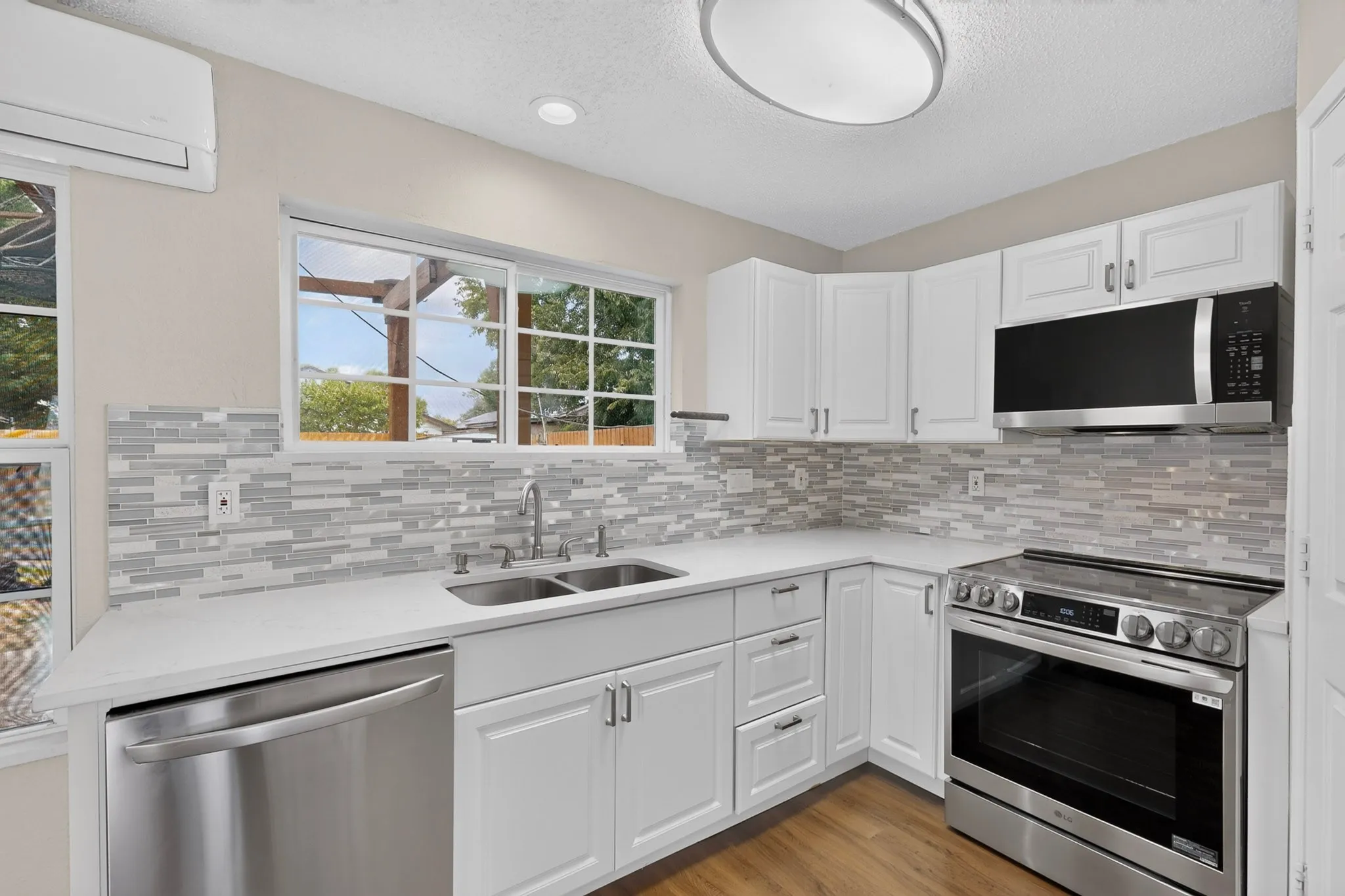 White cabinetry with stainless steel appliances, solid surface countertops, and a full tile backsplash