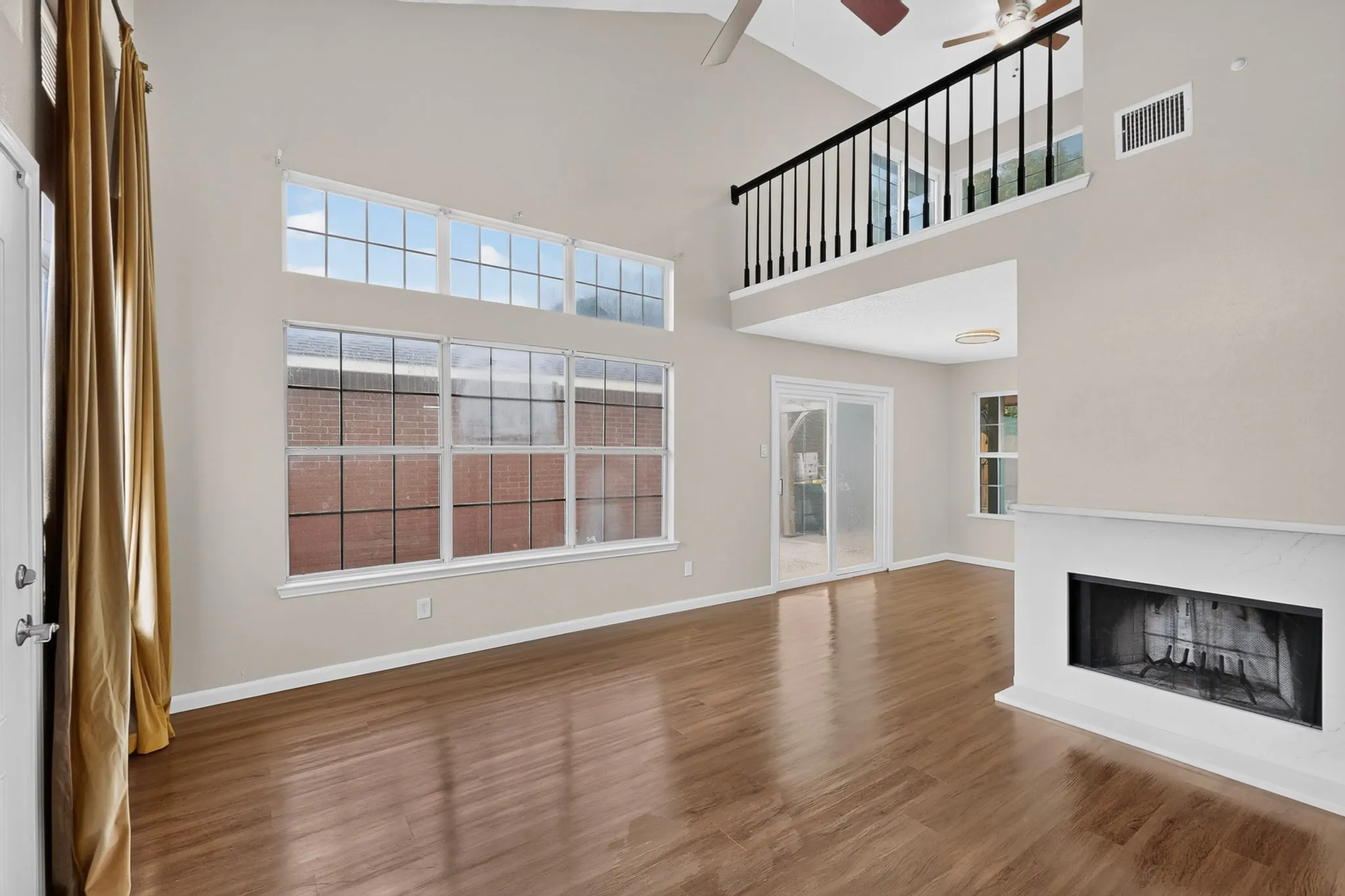 Vaulted ceilings, wood-finish flooring, a contemporary fireplace, and a second-story interior balcony
