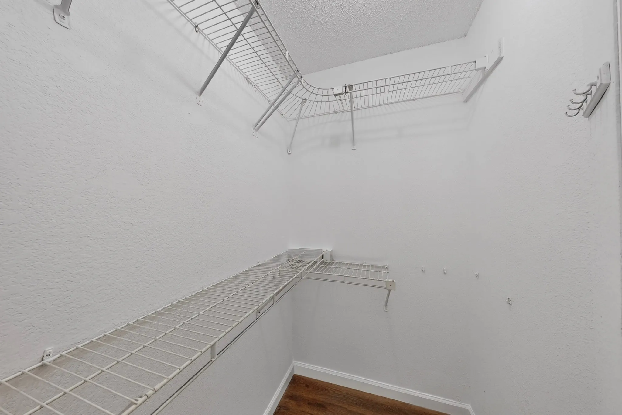 Built-in wire shelving, integrated wall hooks, and wood-finish flooring