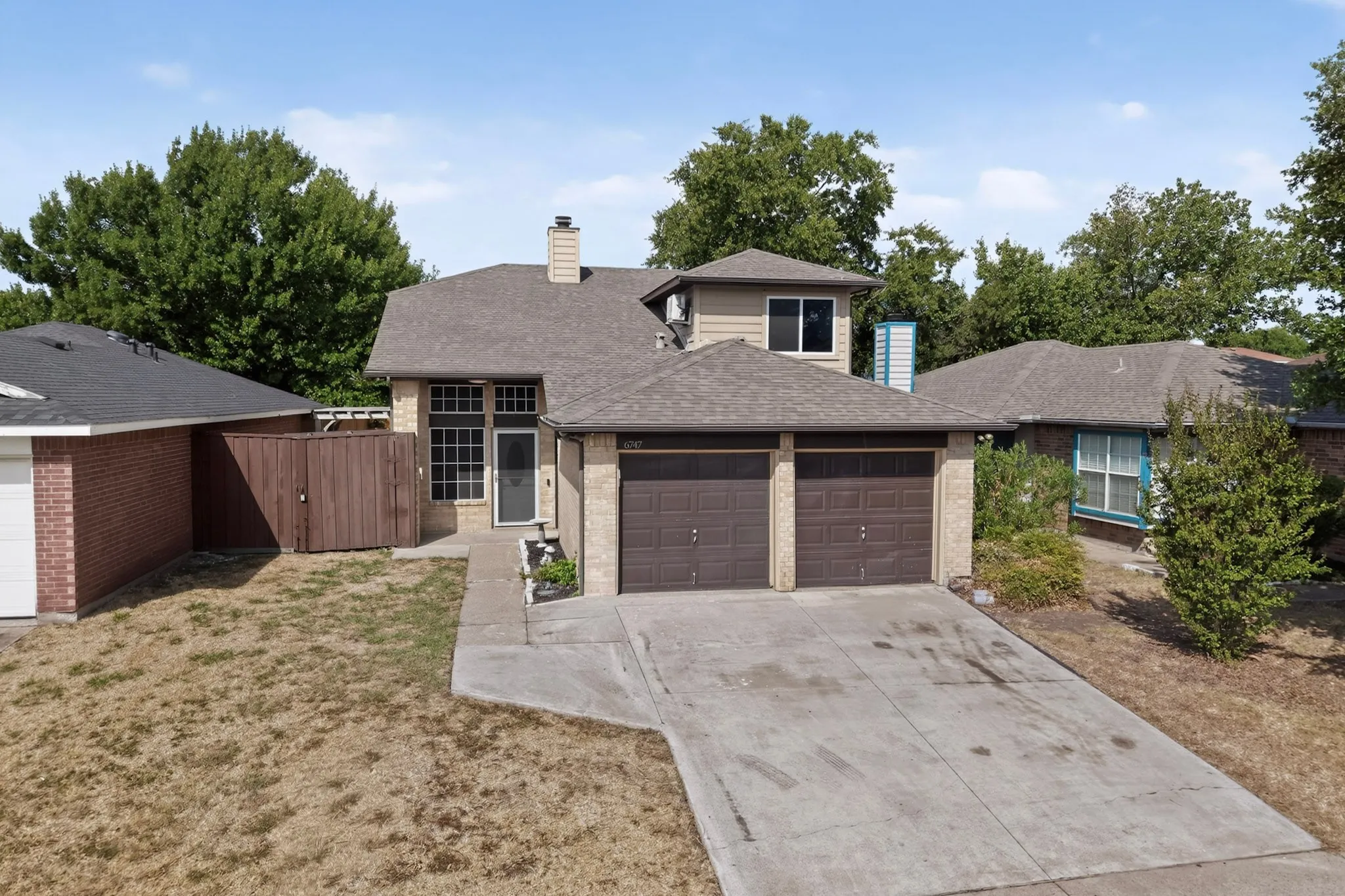 Two-car garage, brick facade, multi-pane windows, covered entry, and a prominent chimney