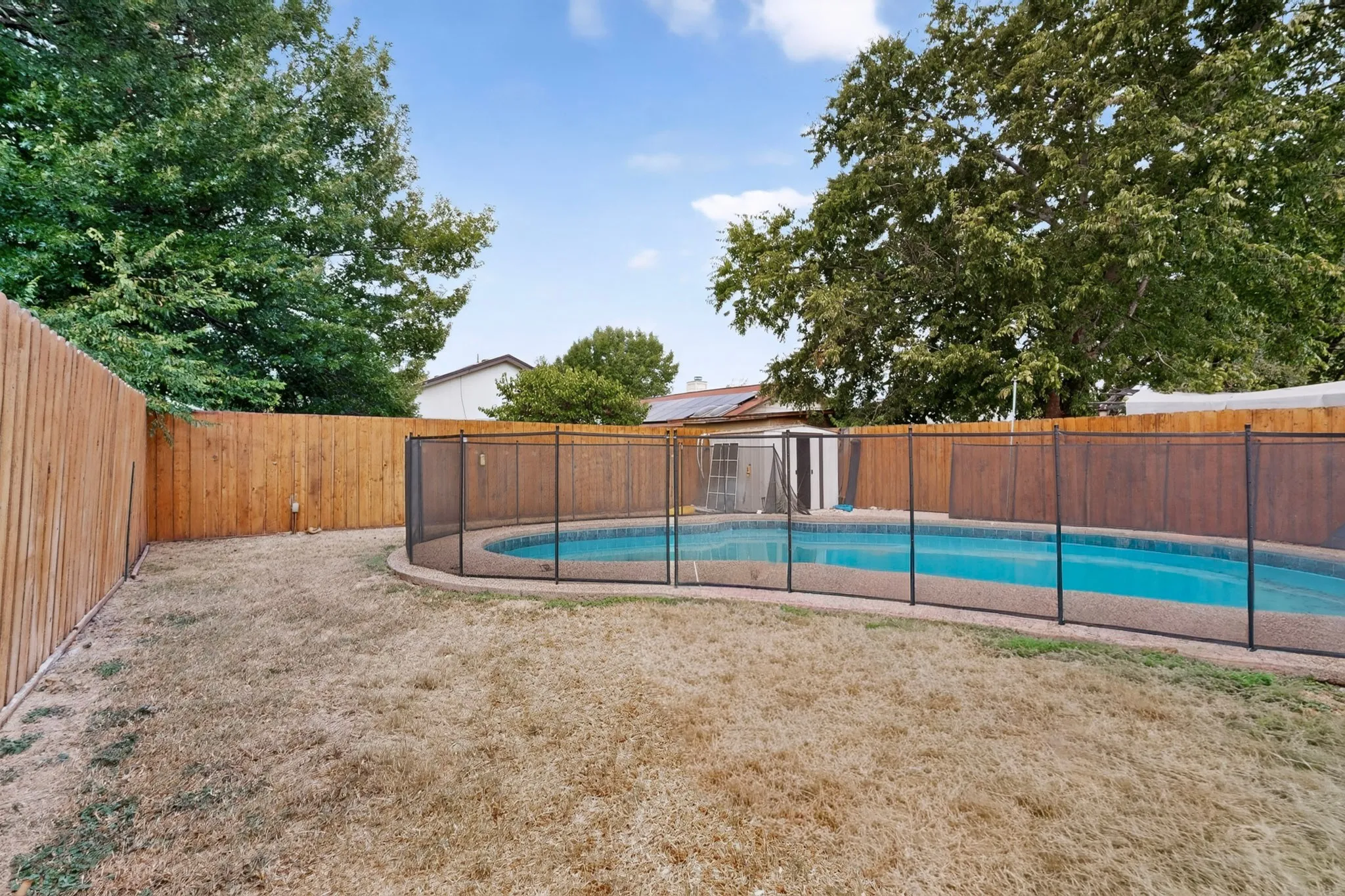 In-ground swimming pool with a black mesh safety fence