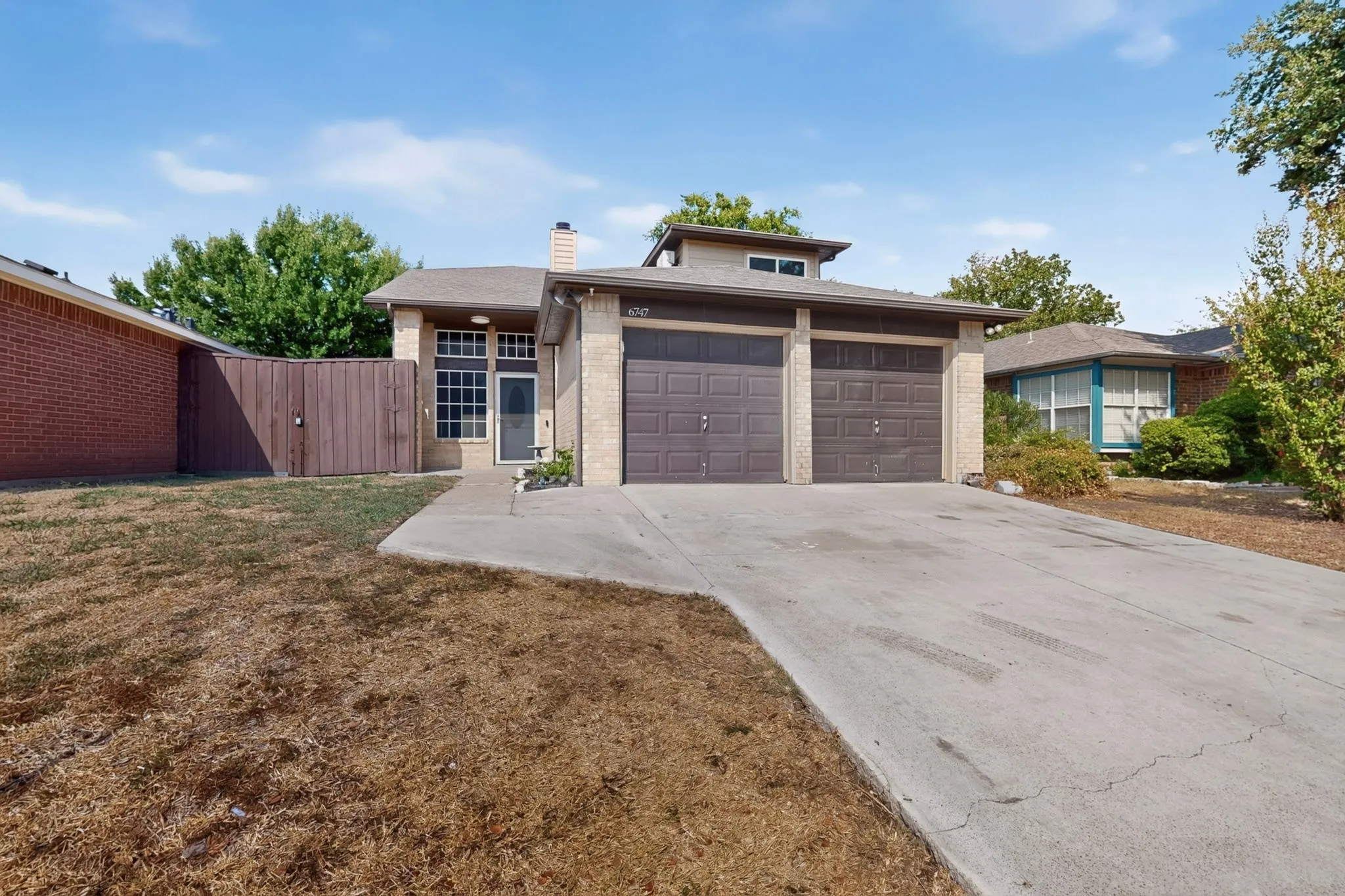 Brick facade with a two-car garage and a concrete driveway