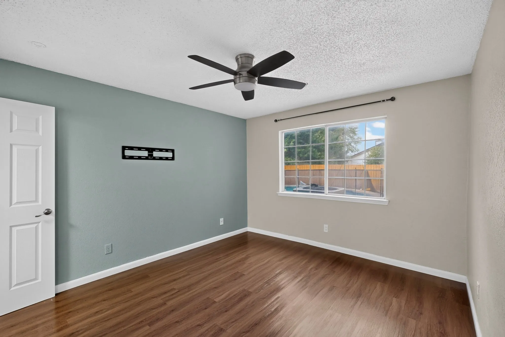 Wood-finish flooring, ceiling fan, and a window providing natural illumination