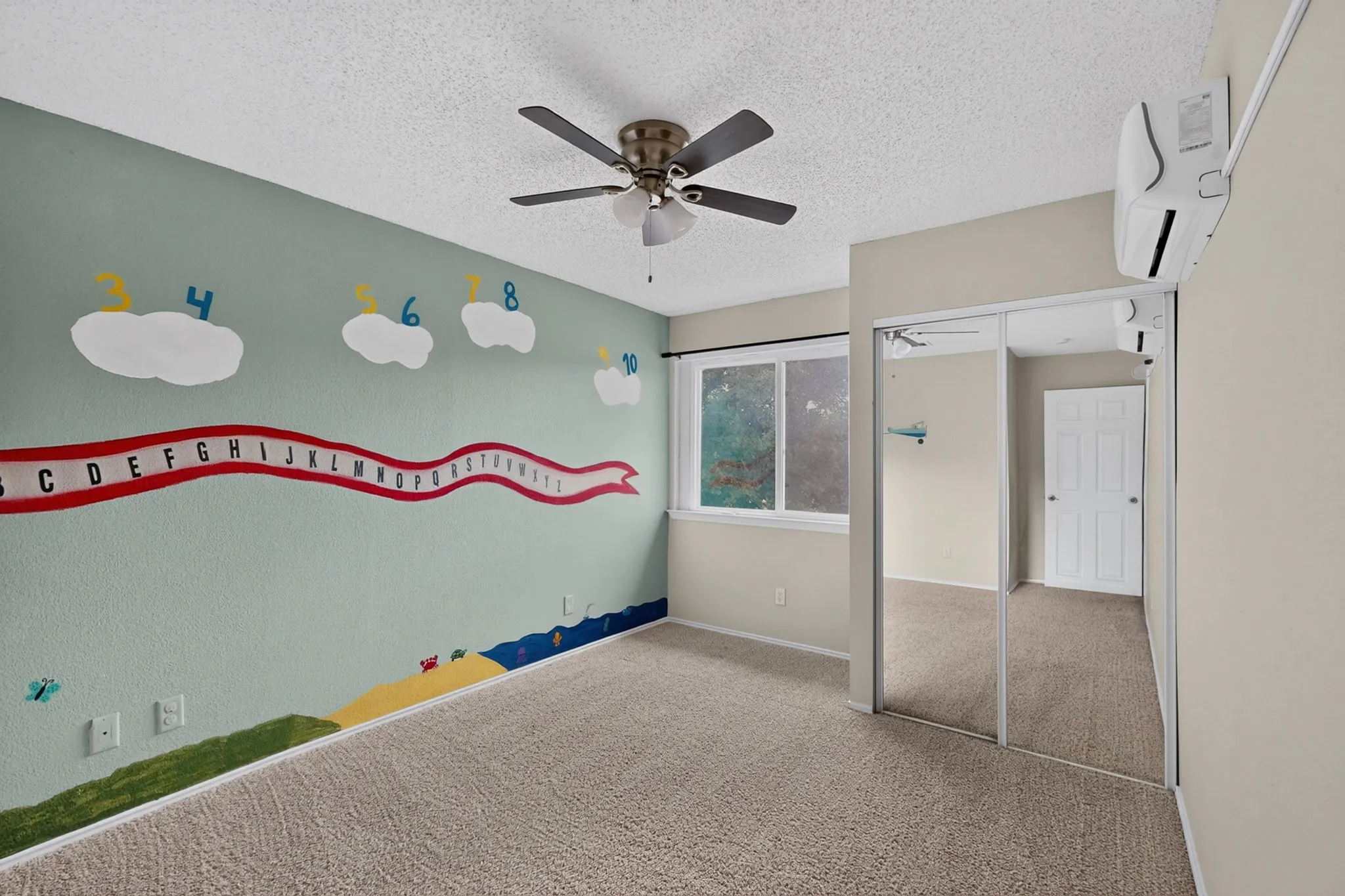 Wall-mounted air conditioning unit, ceiling fan, mirrored closet doors, and carpeted flooring