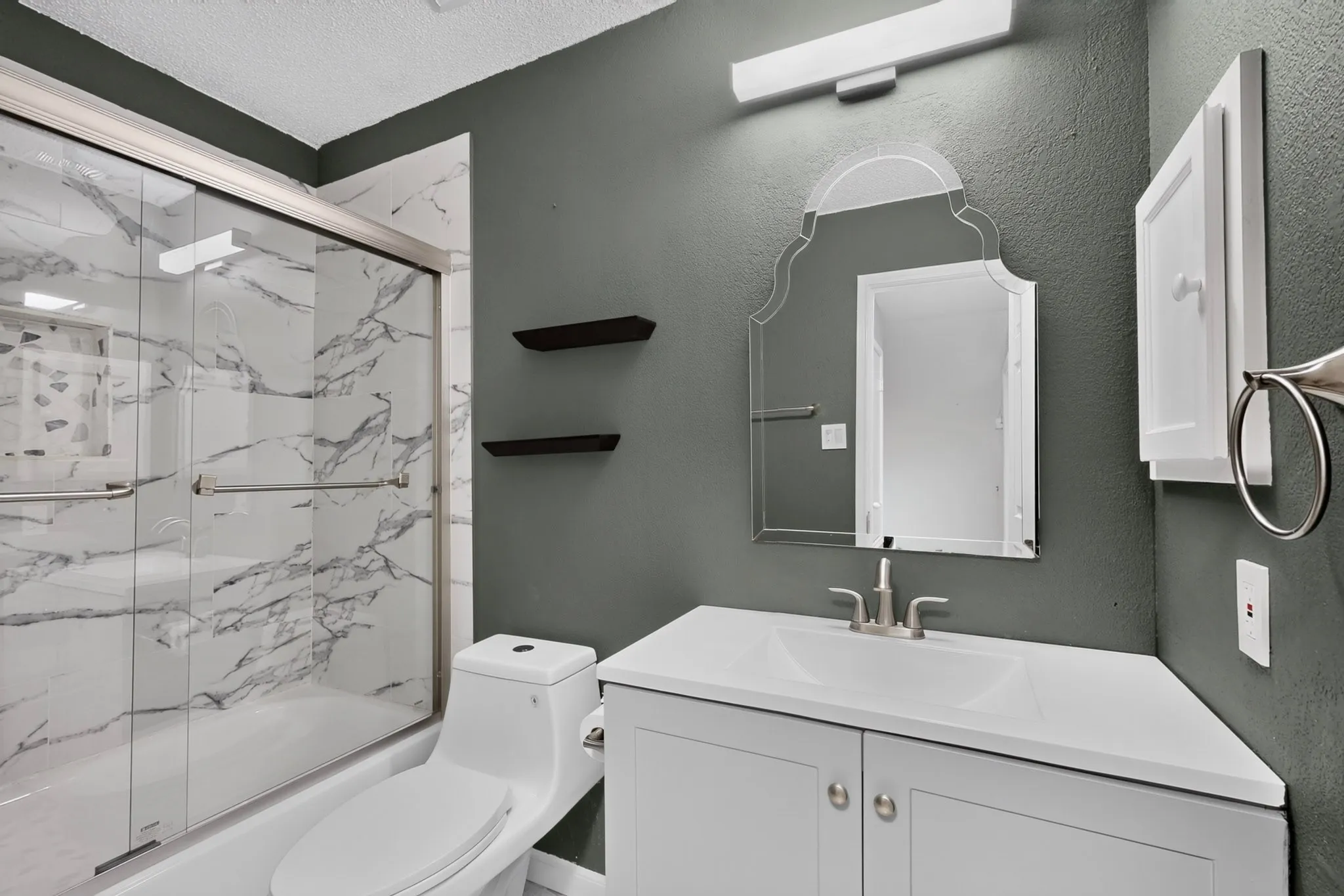 Walk-in shower with sliding glass doors and marble-style tile surround
