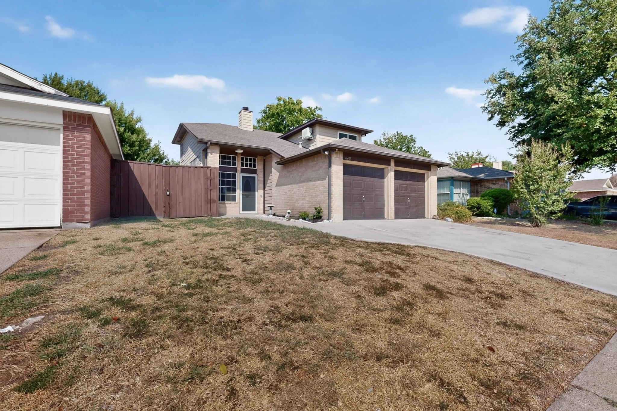 Brick and siding exterior, front entry with transom window, concrete driveway, two-car garage, and partial wood fence