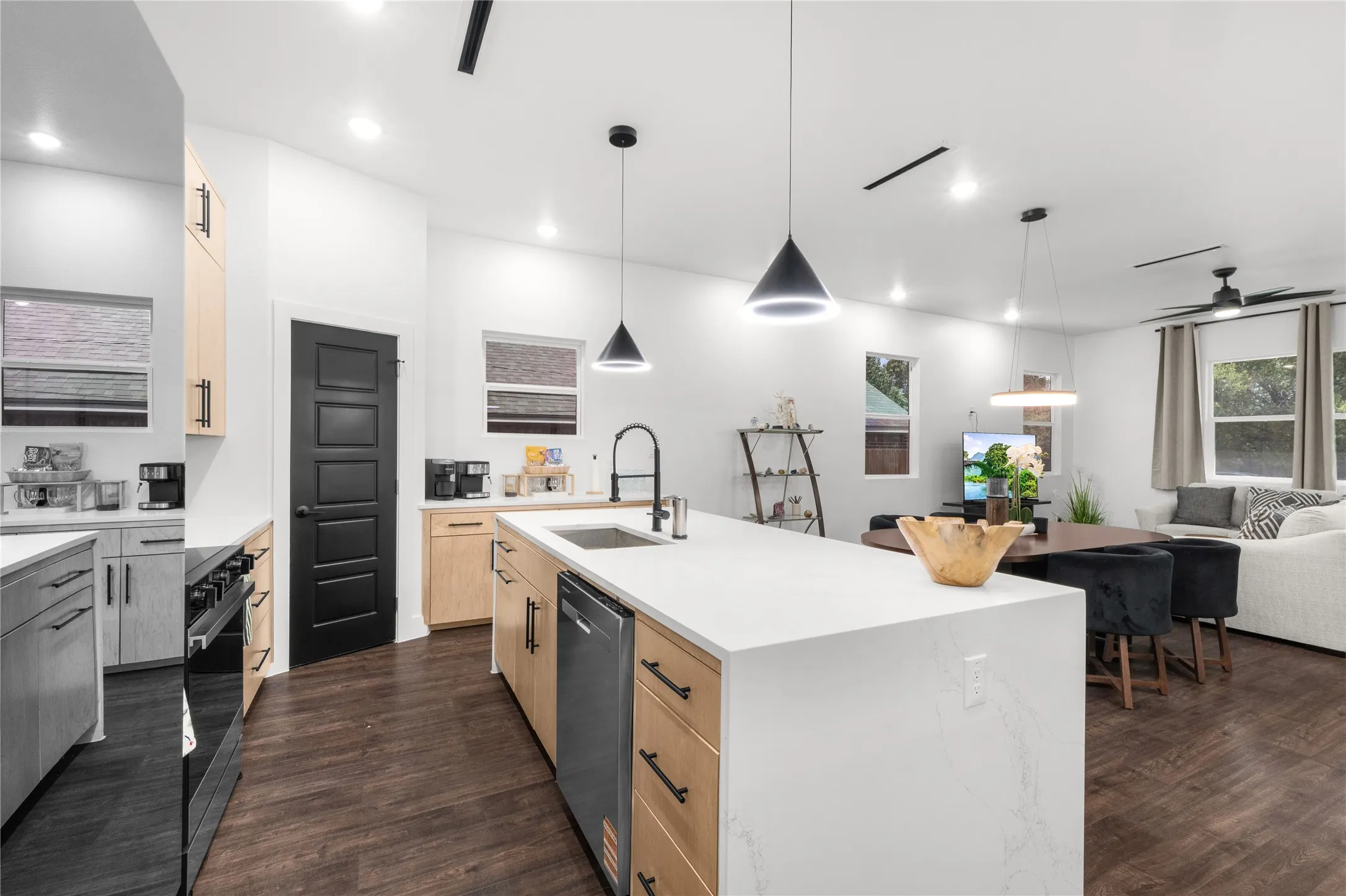 Kitchen with a large island featuring a sink and dishwasher, wood-finish flooring, recessed lighting, and a range with an oven