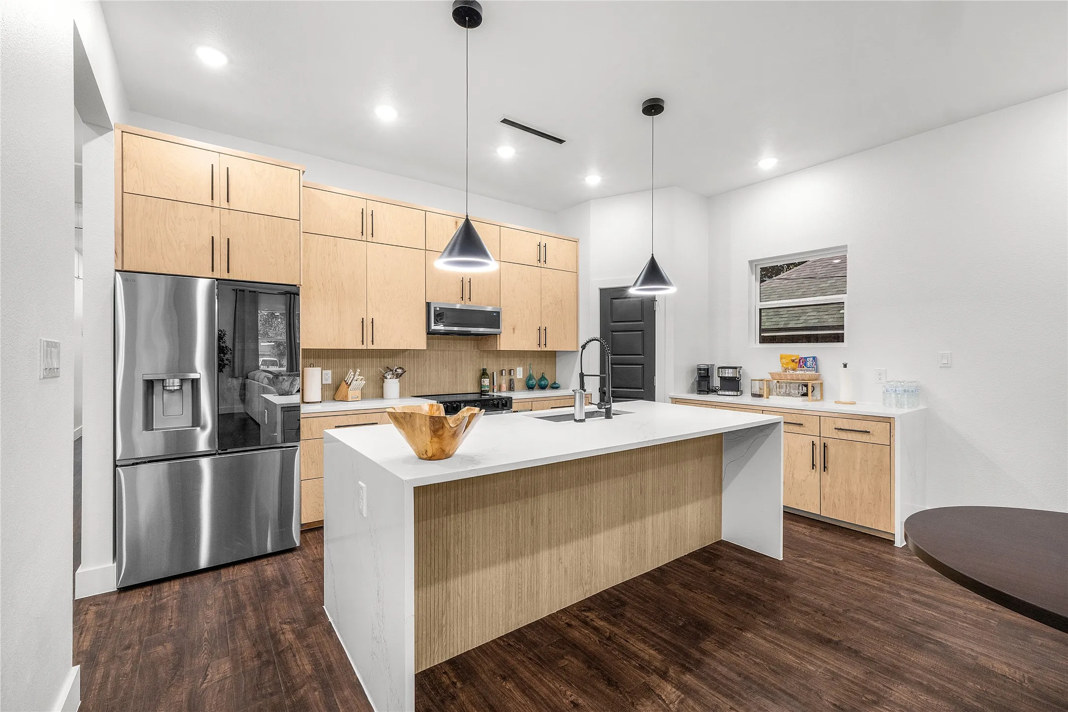 Kitchen featuring wood-finish flooring, light wood cabinetry, stainless steel appliances, a center island with a white countertop, and recessed lighting