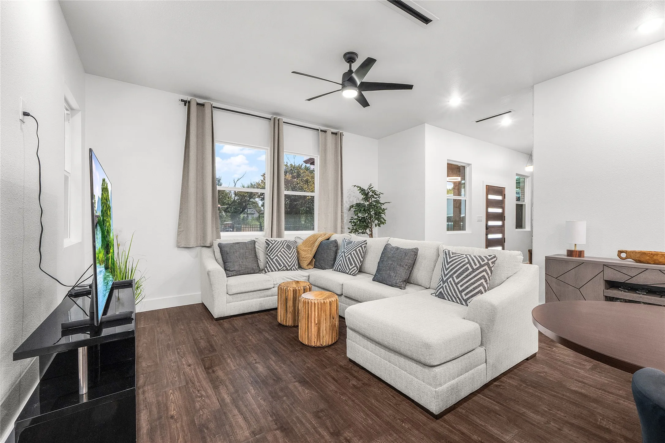 Expansive living area featuring wood-finish flooring, multiple windows, recessed lighting, and a ceiling fan