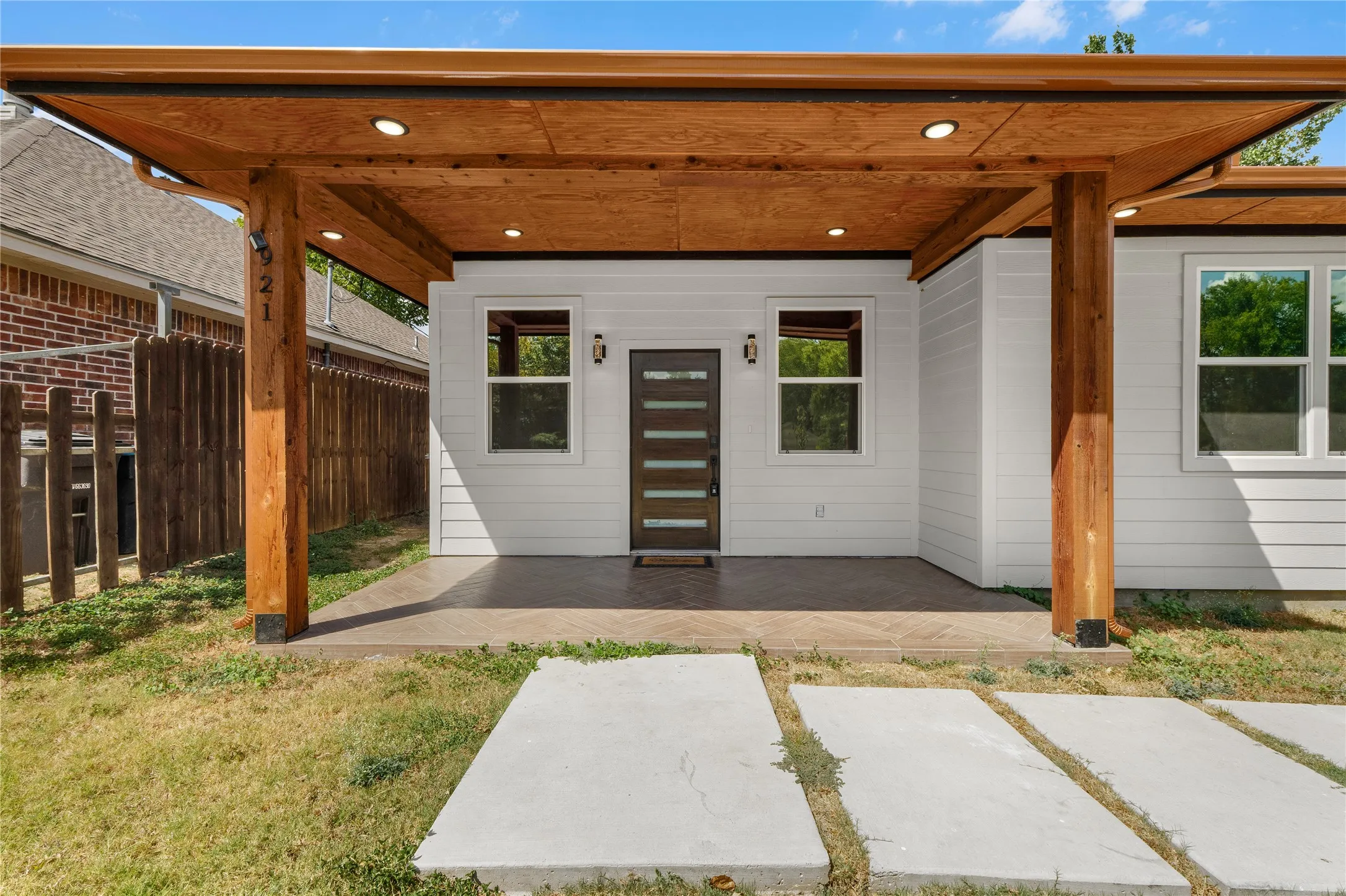 White horizontal siding exterior with a wood-clad overhang supported by timber posts