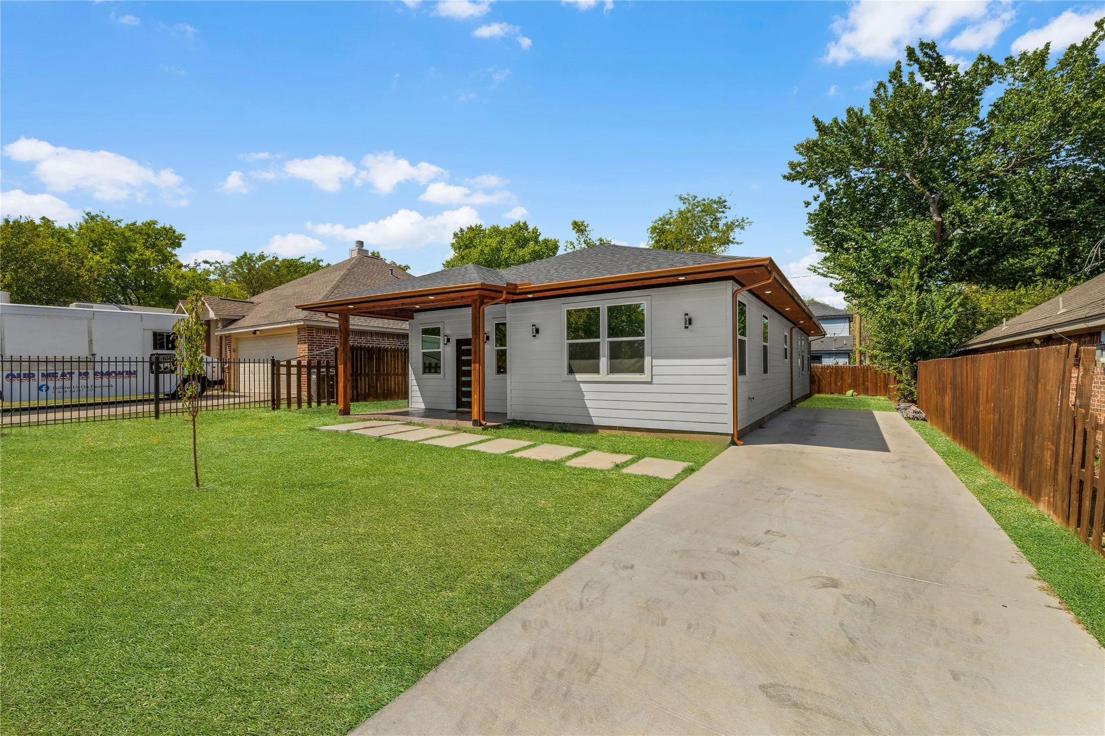 Contemporary exterior with light gray siding, wood-toned soffit, and dark fascia
