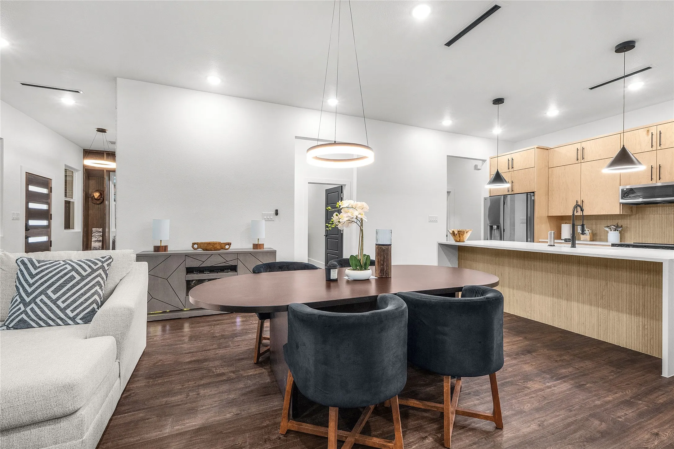 Open-concept living space featuring wood-finish flooring, recessed lighting, and a contemporary light fixture