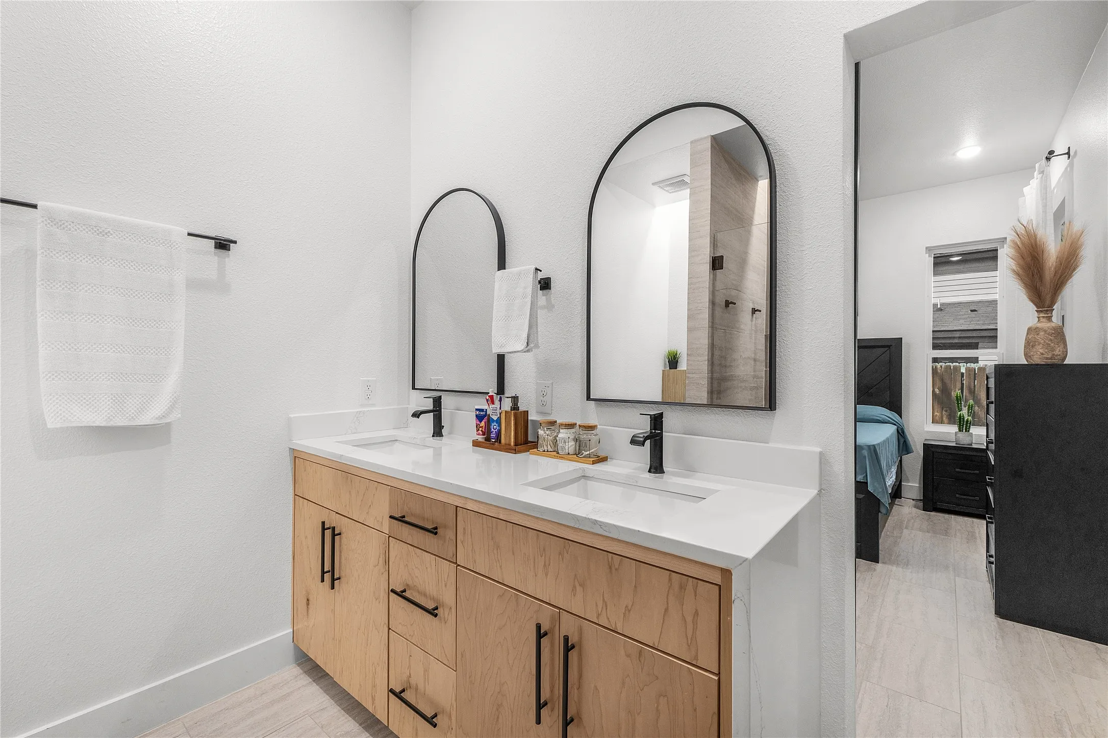 Dual vanity with undermount sinks, light wood-finish cabinetry, white countertops, and black hardware