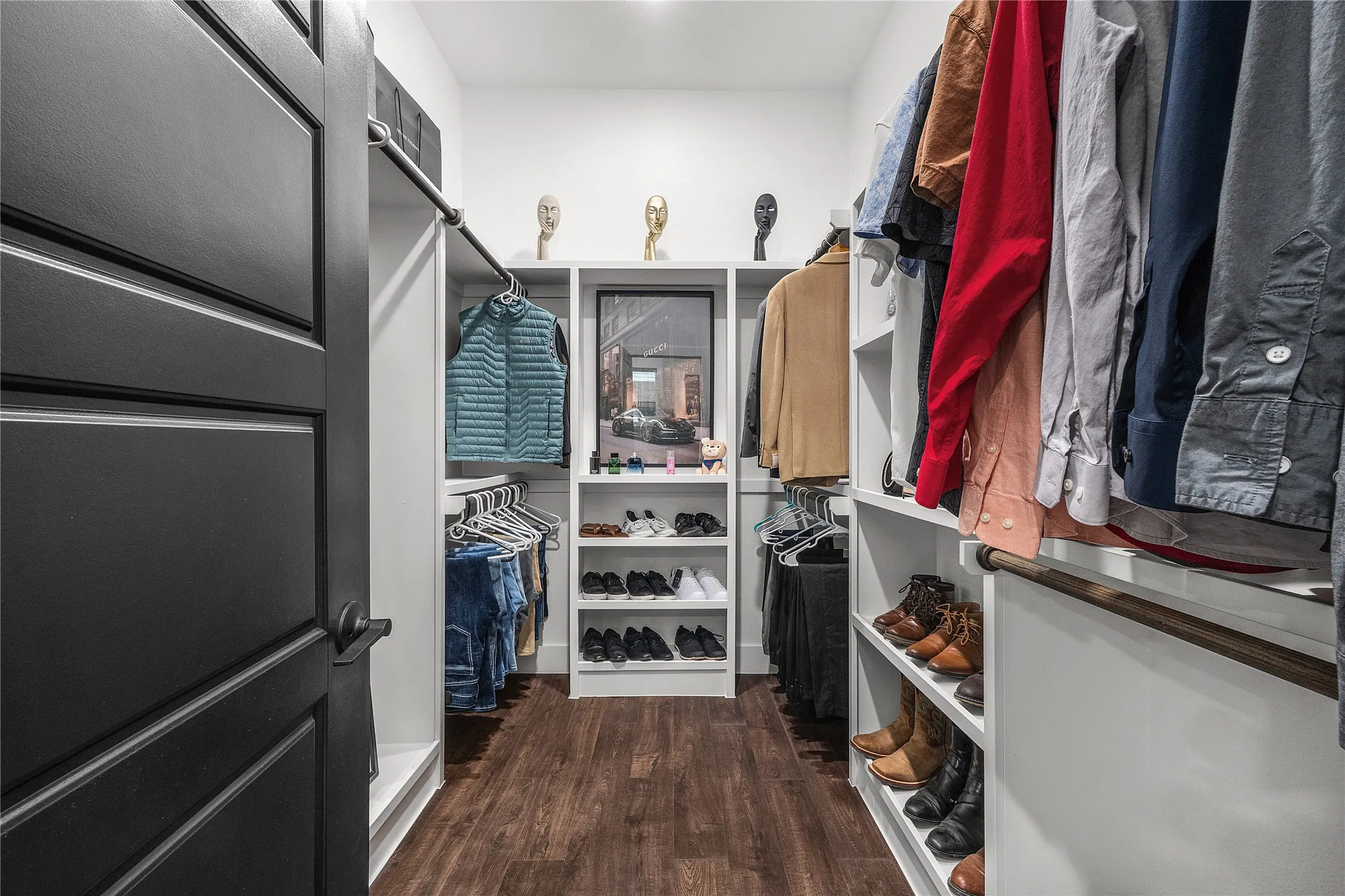 Walk-in closet featuring wood-finish flooring, built-in shelving, and a dark-framed window