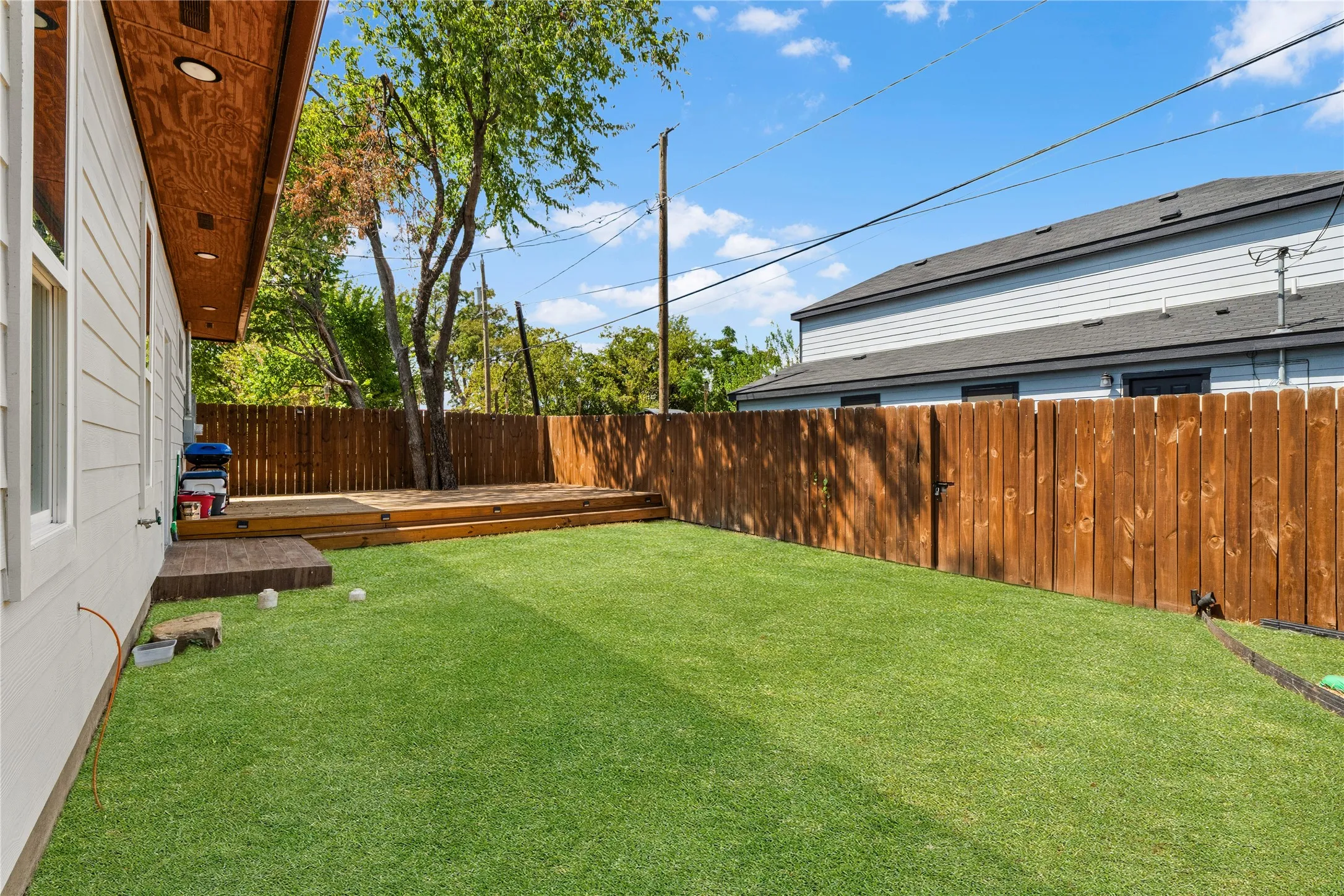Expansive backyard featuring artificial turf, a multi-level wood deck, and a tall wood privacy fence