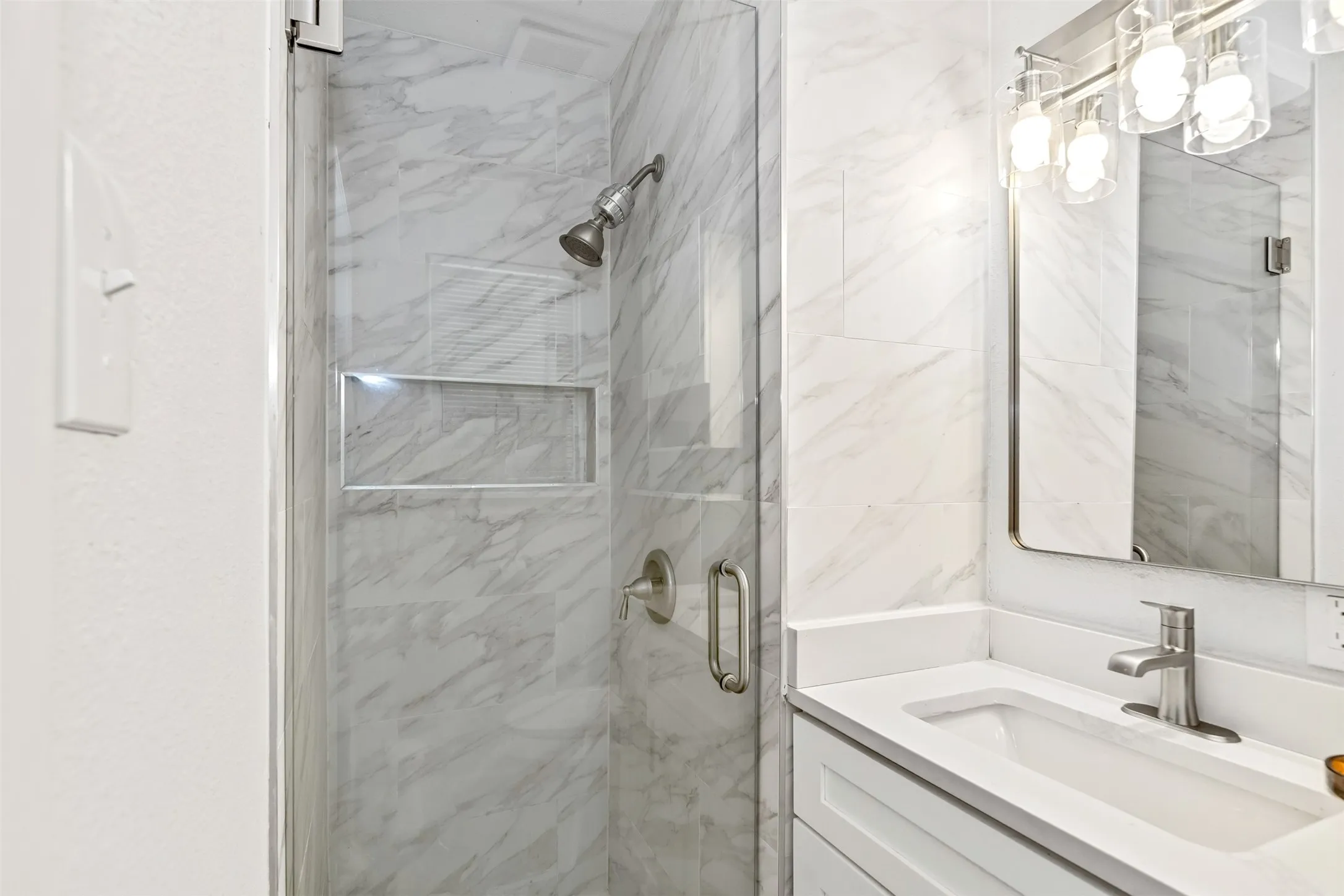 Walk-in shower with clear glass enclosure and recessed niche