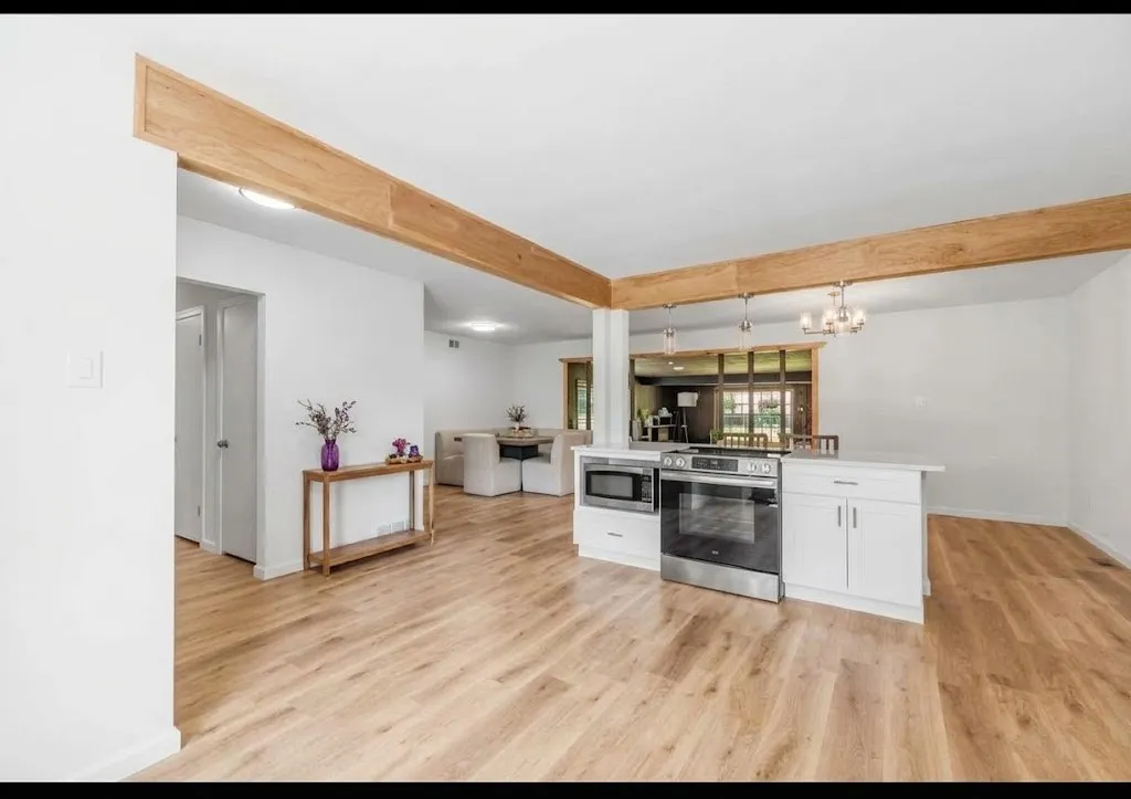 Wood-finish flooring throughout, white cabinetry, stainless steel oven, and microwave