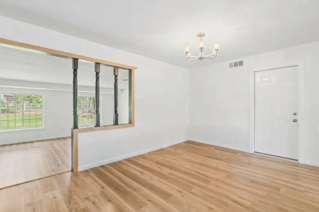Wood-finish flooring throughout, white walls, and a recessed partition with decorative spindles