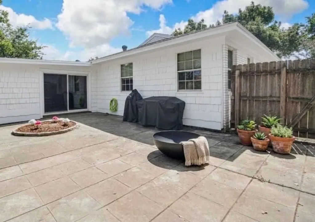 Paved patio with an elevated planting bed and a wooden privacy fence