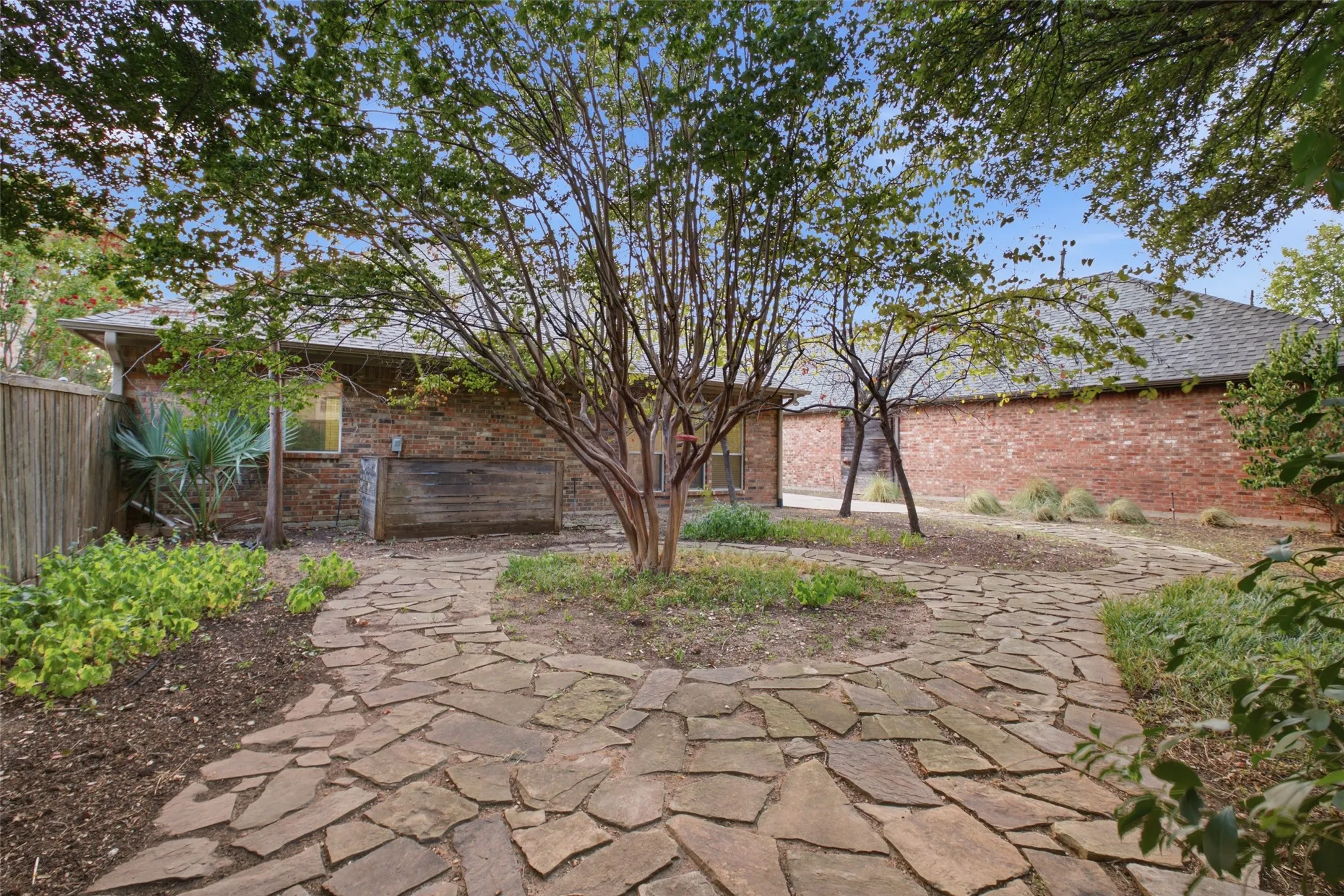 Fully fenced yard with a winding flagstone path and mature trees