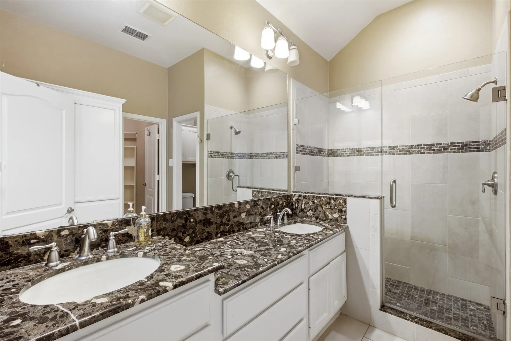 Double vanity with stone-finish countertop, dual undermount sinks, and brushed nickel fixtures