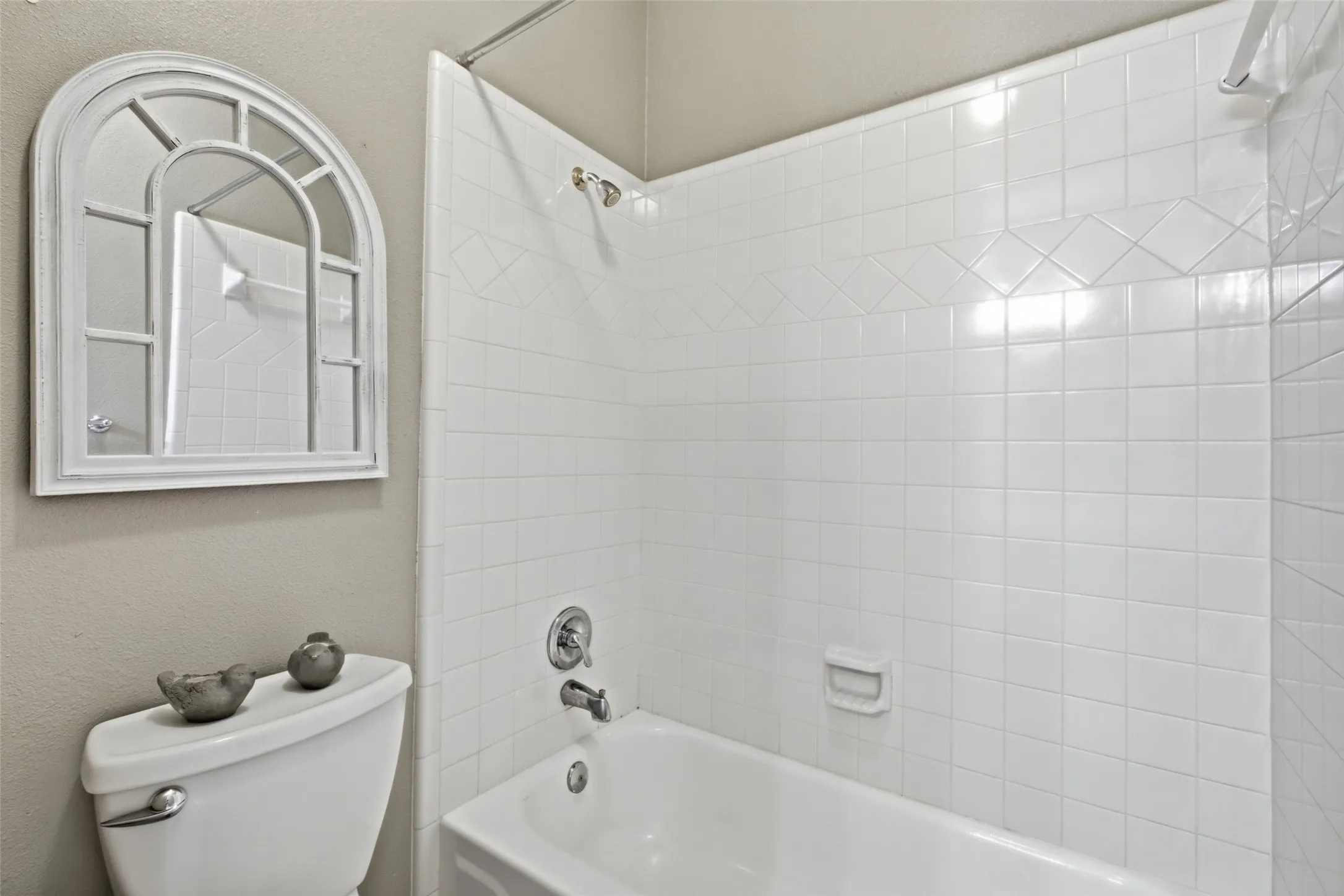 Crisp tub-and-shower combo with full tile surround, clean and ready for guests