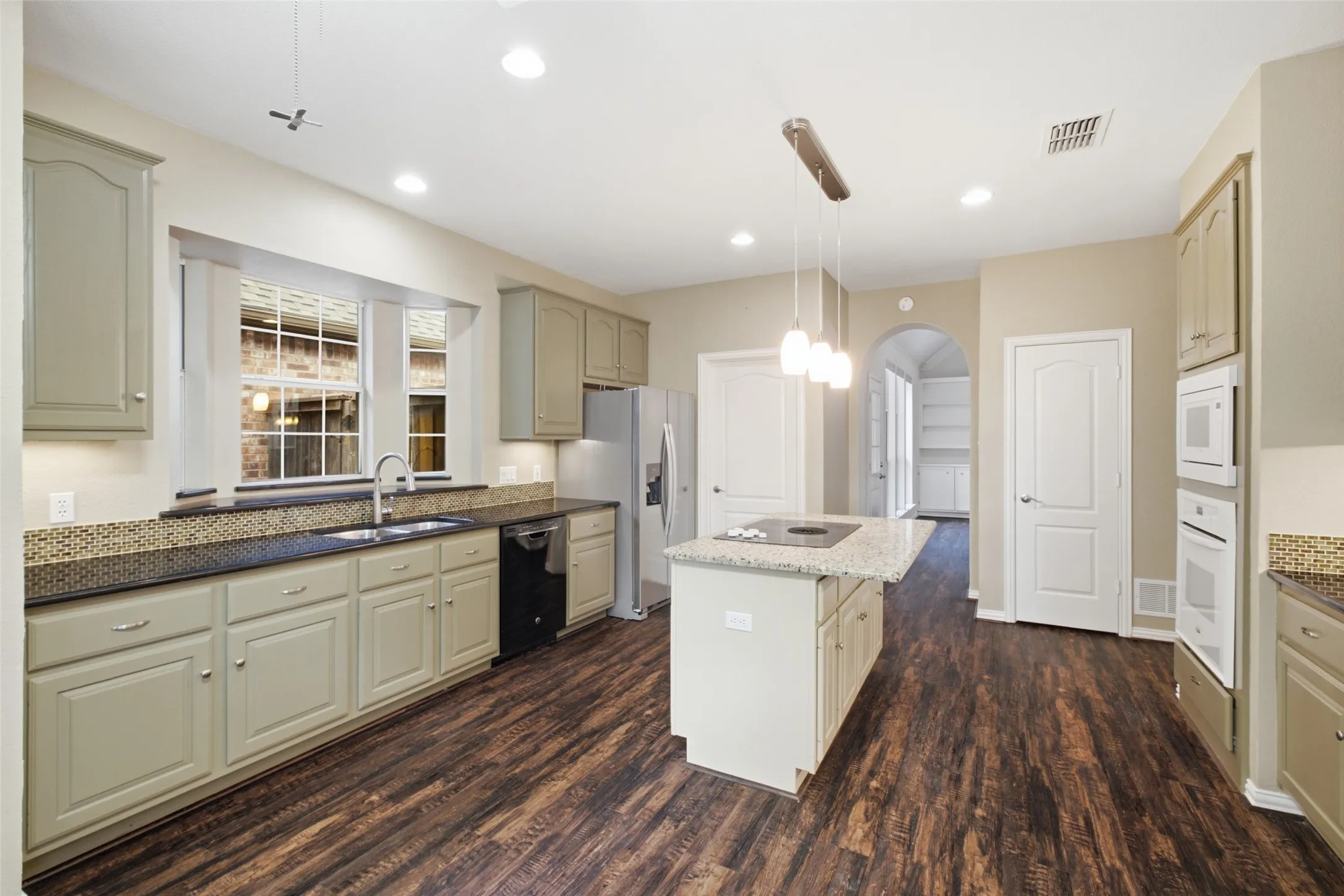 Cabinetry for days: granite counters, glass mosaic backsplash, deep runs of storage on every wall