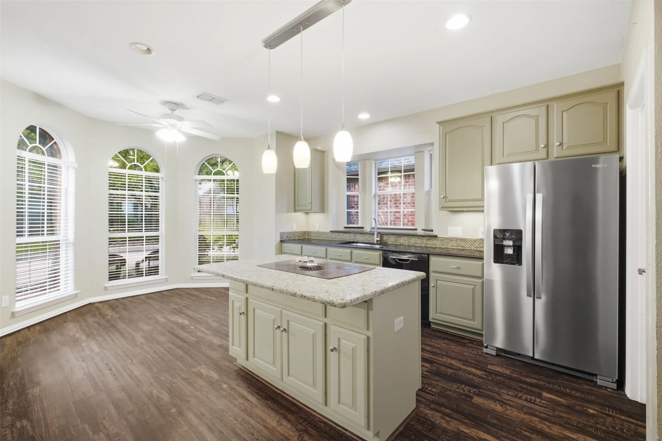 Chef's kitchen, 14'9" x 19' — granite island cooktop, stainless appliances and a bay of arched windows