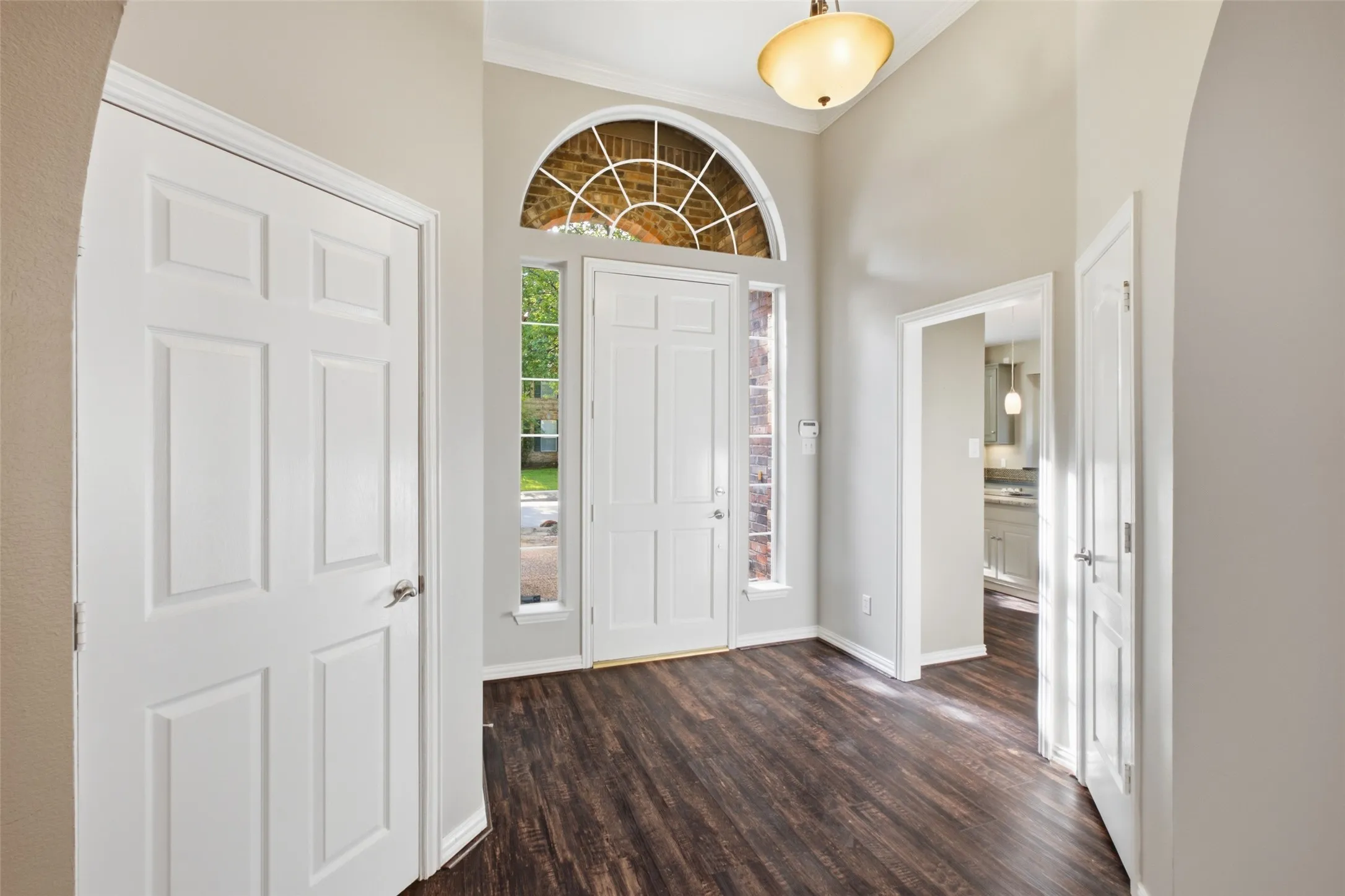 Arched transom and full sidelights pour daylight into a soaring entry — the whole home starts bright