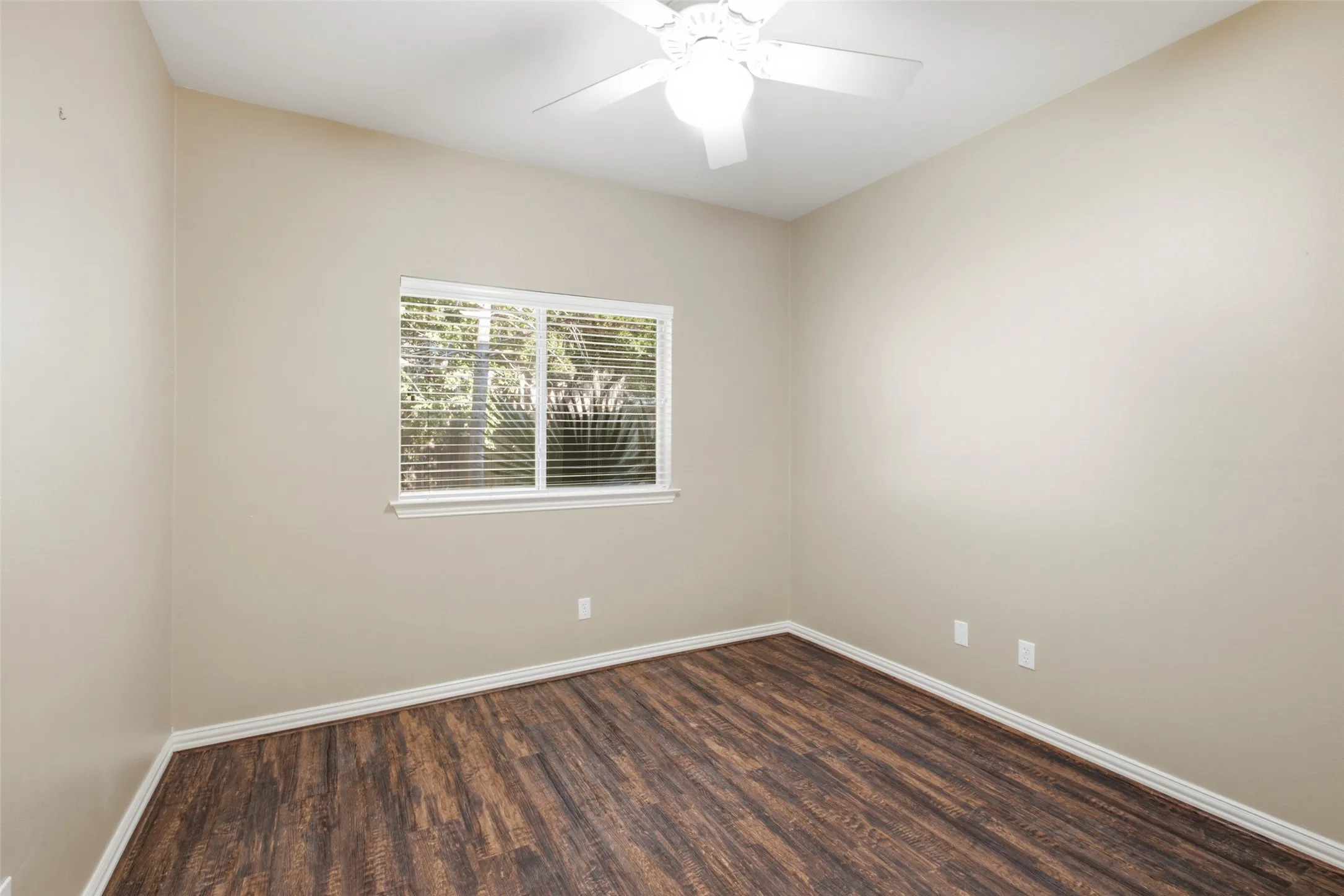 Peaceful third bedroom looking out on mature landscaping — quiet enough for a work-from-home desk