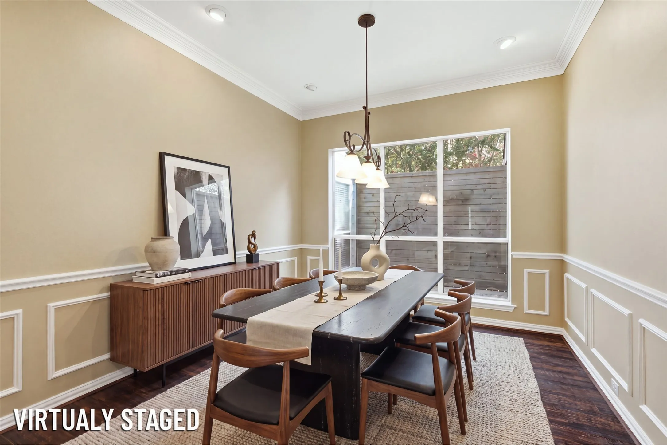 (Virtually Staged) Formal dining in full wainscoting and crown, with a wrought-iron chandelier and garden window