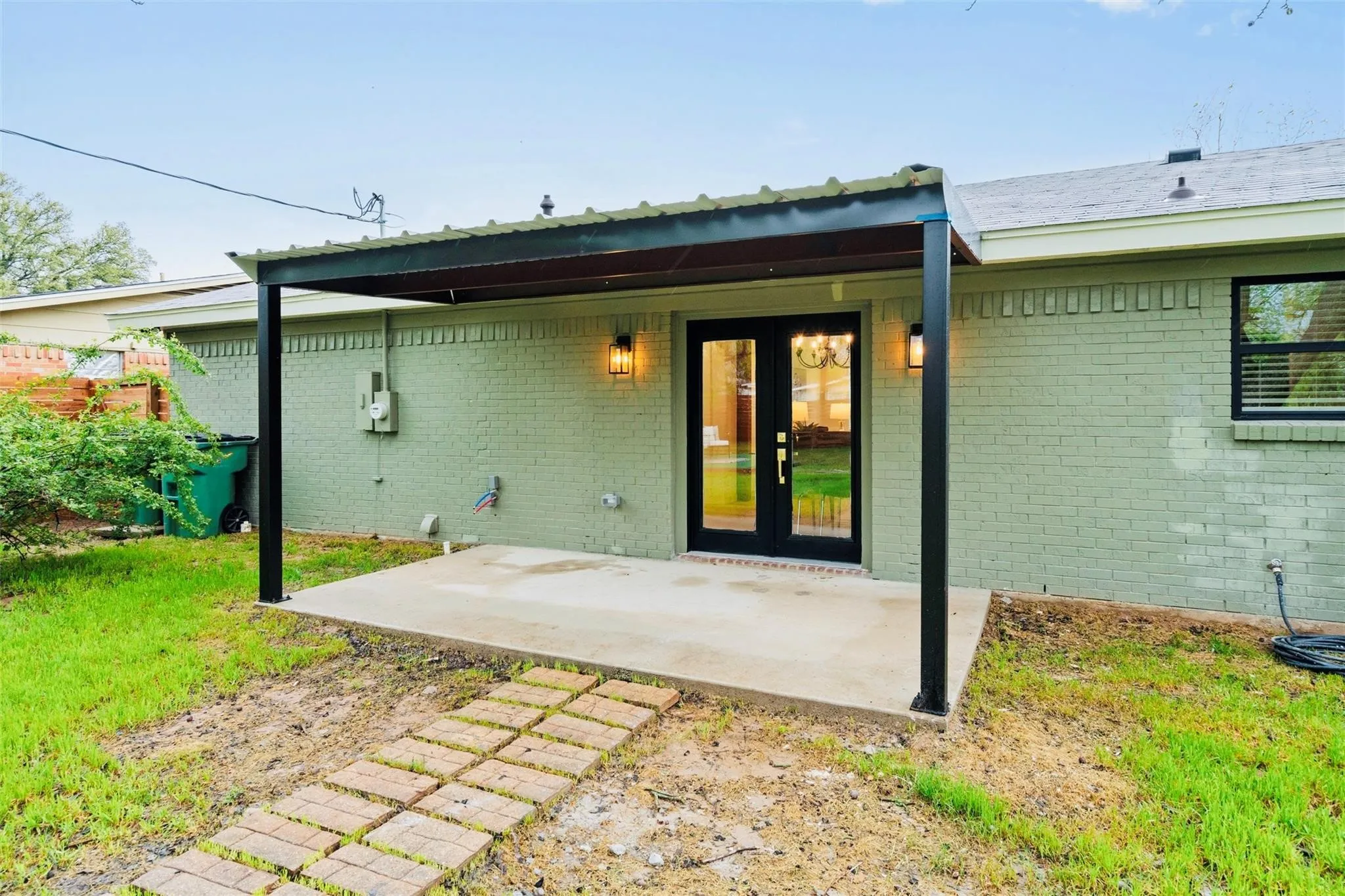 Covered patio with concrete slab and brick paver pathway