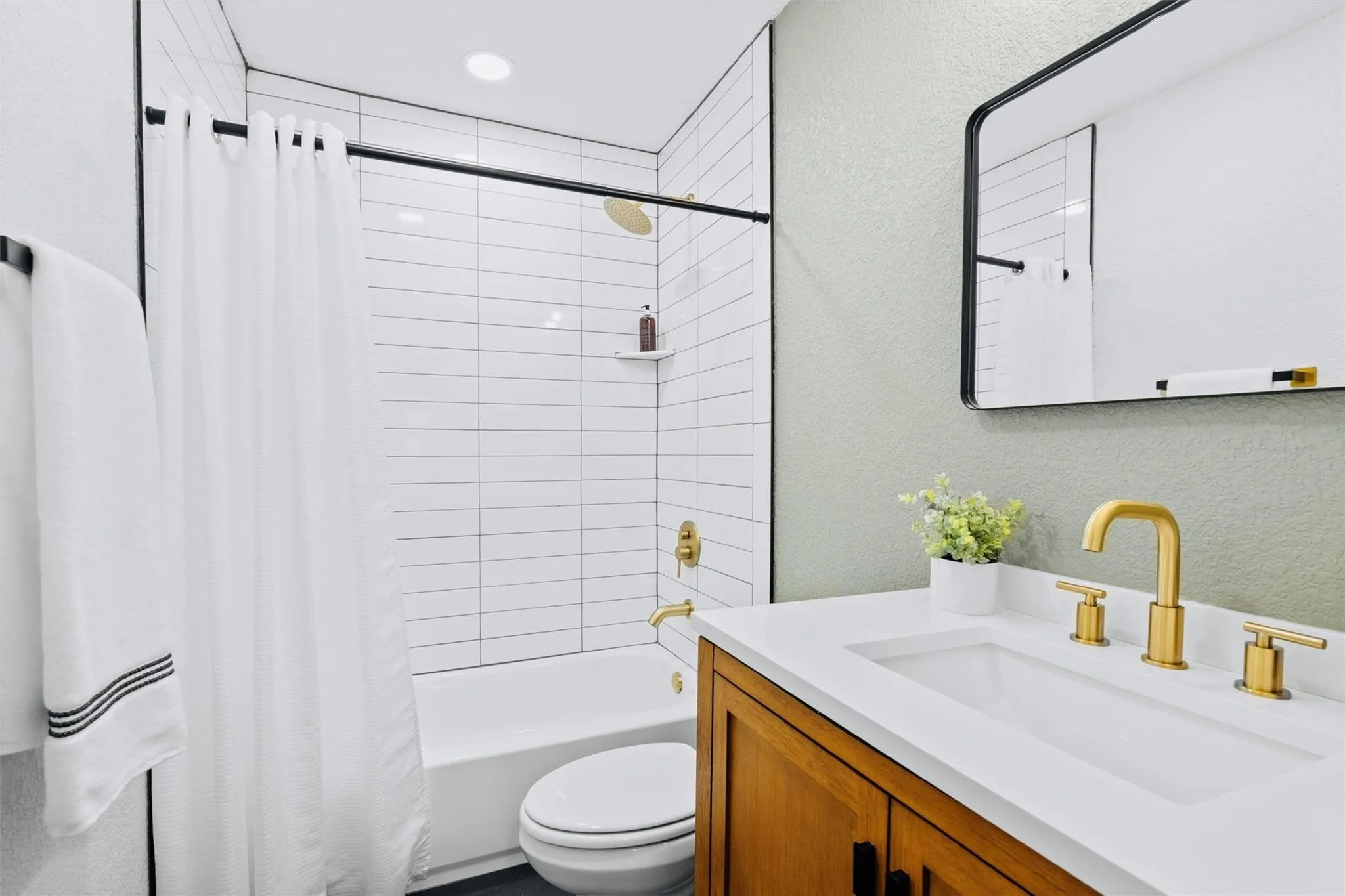 Integrated vanity with white countertop and sink, gold-finish faucet, and wood-finish cabinetry