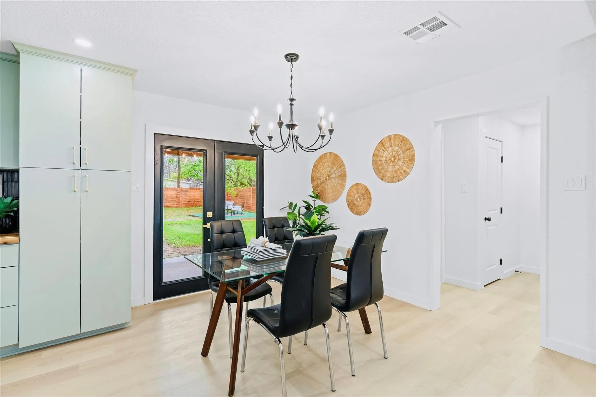 Light wood-finish flooring, recessed lighting, and a chandelier illuminate the dining area