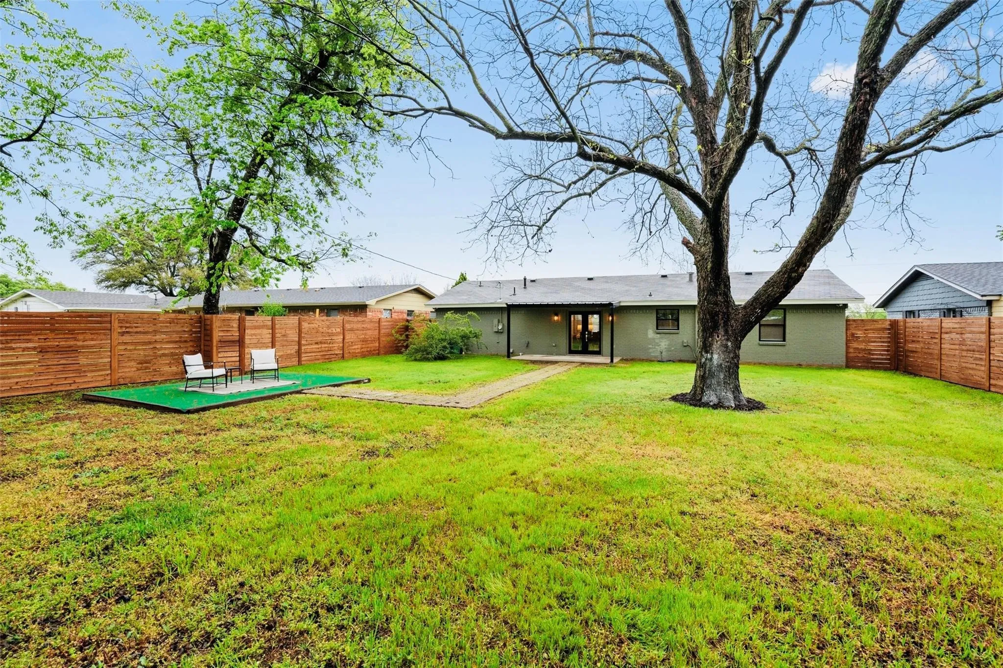 Spacious backyard with mature trees, privacy fencing, and a dedicated patio area