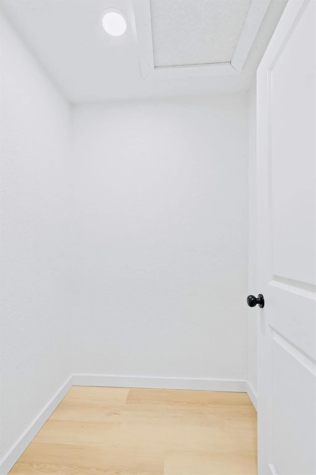 Wood-finish flooring, recessed lighting, white interior door, and black door hardware
