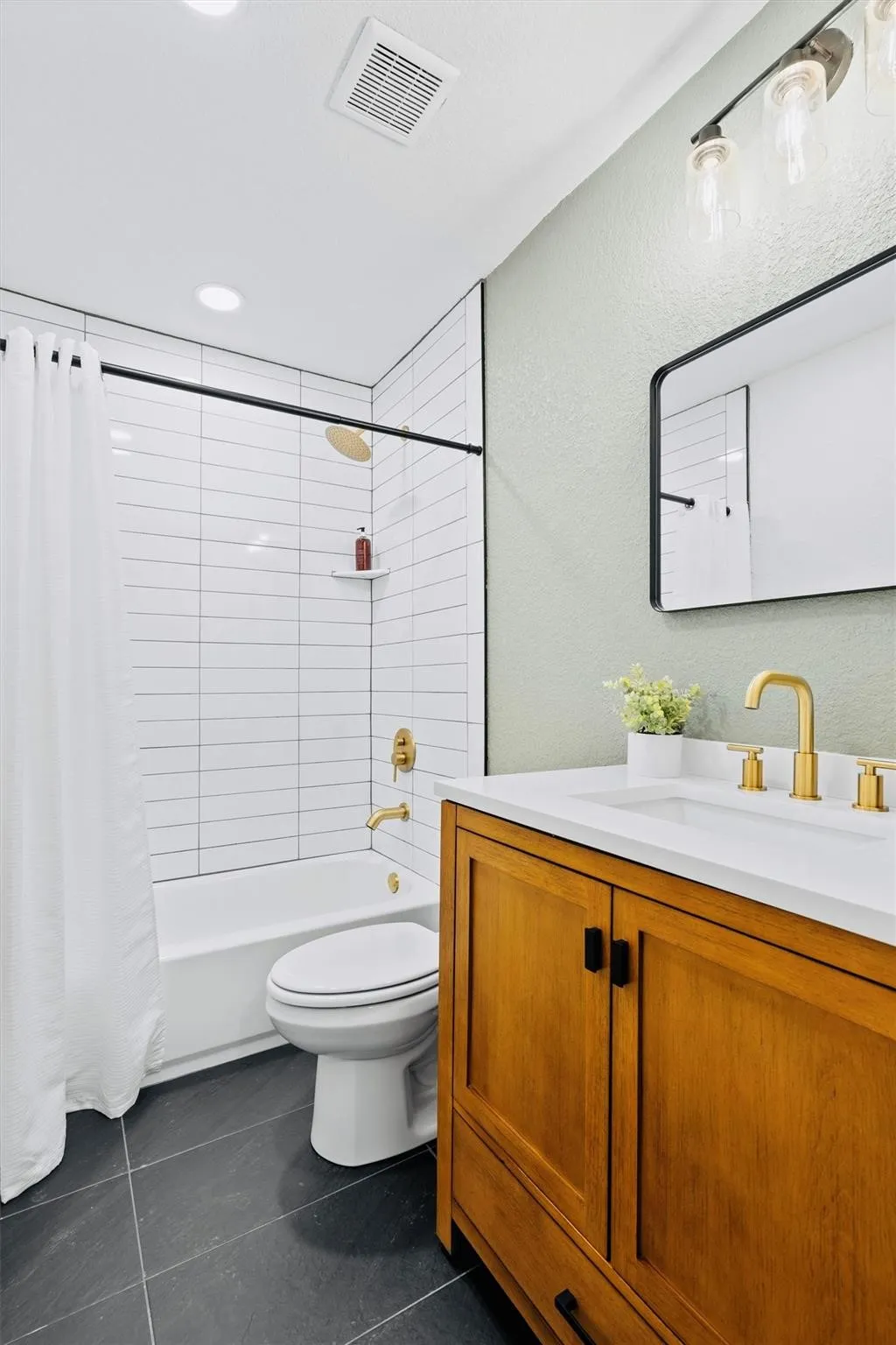 Bathroom featuring a single vanity with a white countertop, gold-finish faucet, and wood-finish cabinetry