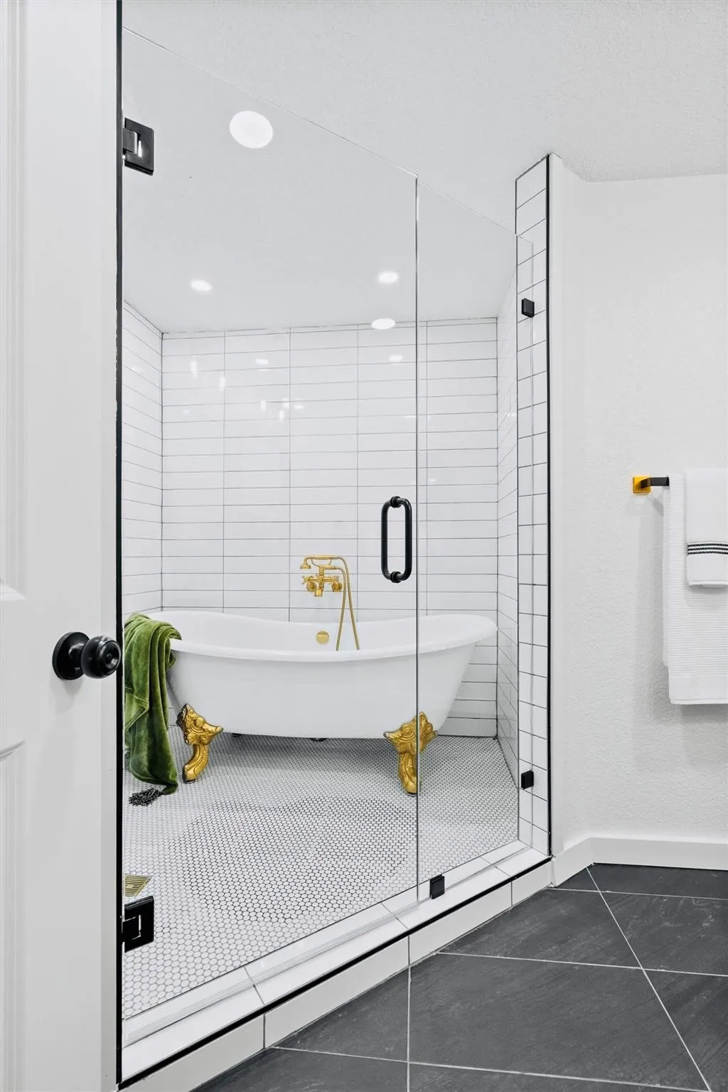 Glass-enclosed shower with a clawfoot tub, white subway tile walls, and a white hexagonal tile floor