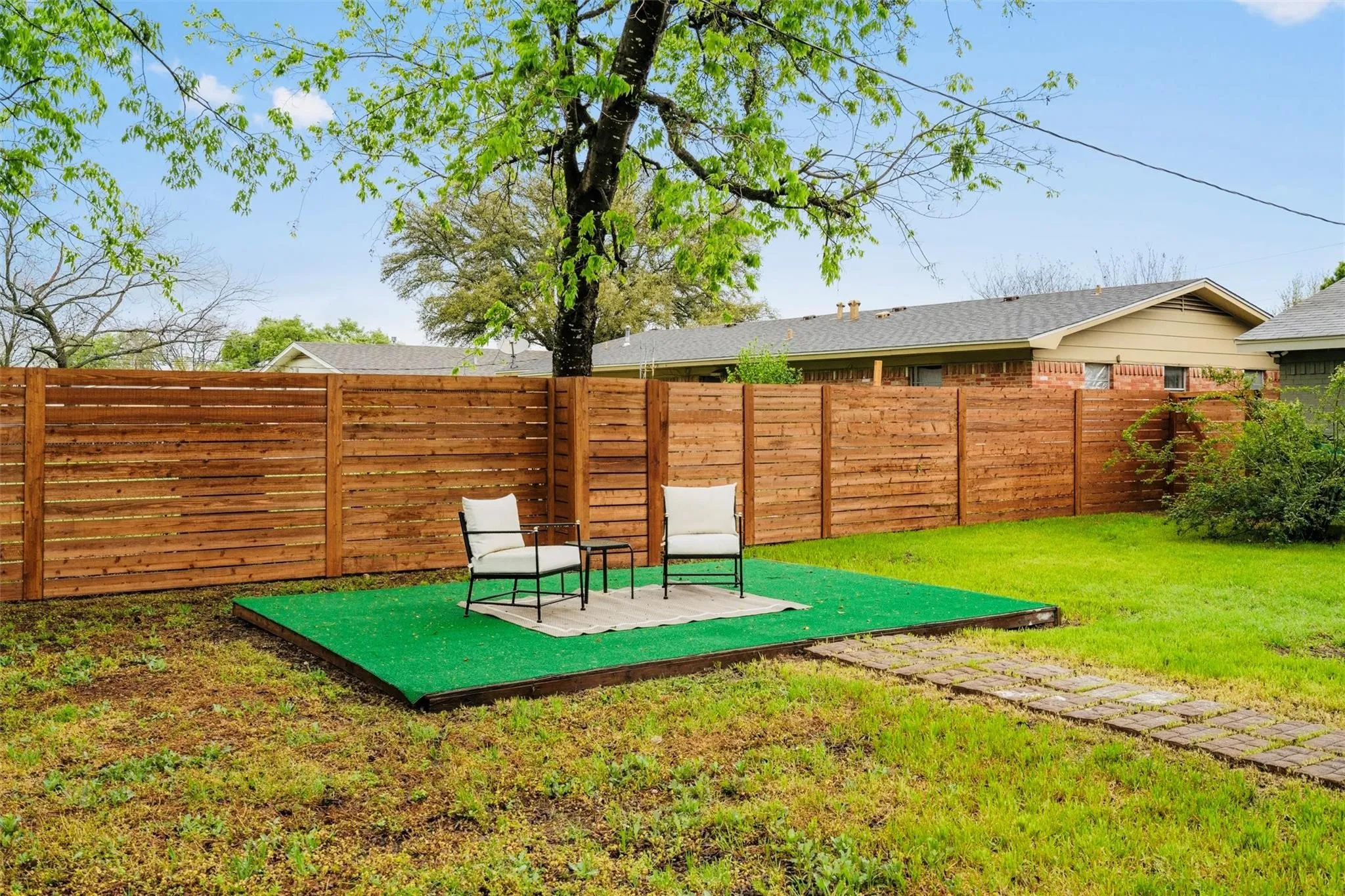 Expansive backyard featuring a natural wood fence and a green turf patio area