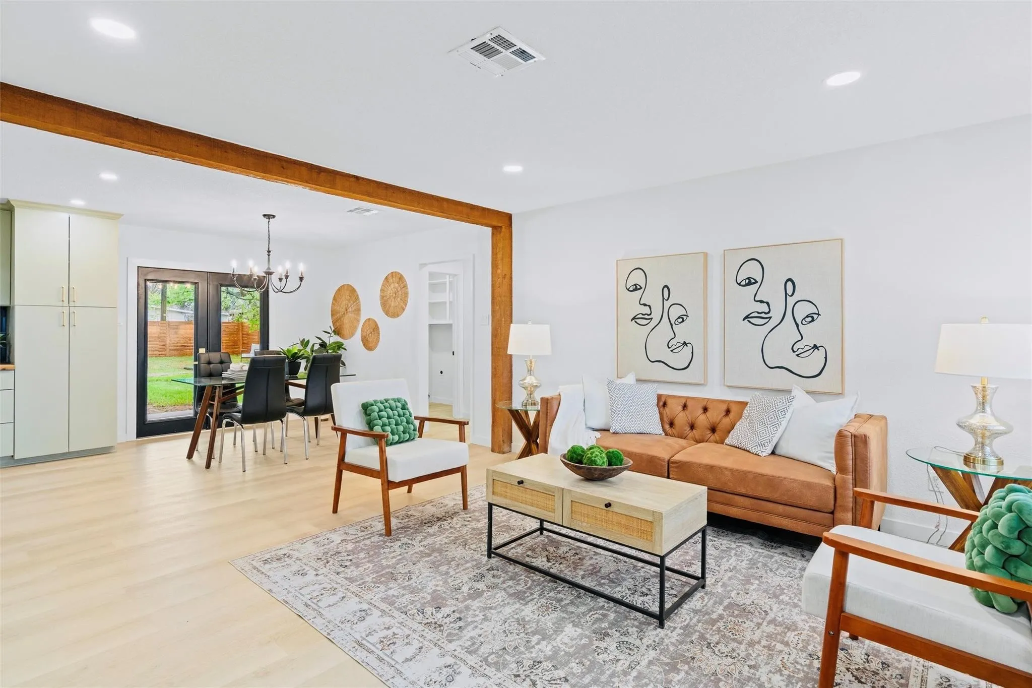 Open concept living space with light wood-finish flooring, recessed lighting, and exposed wood beam