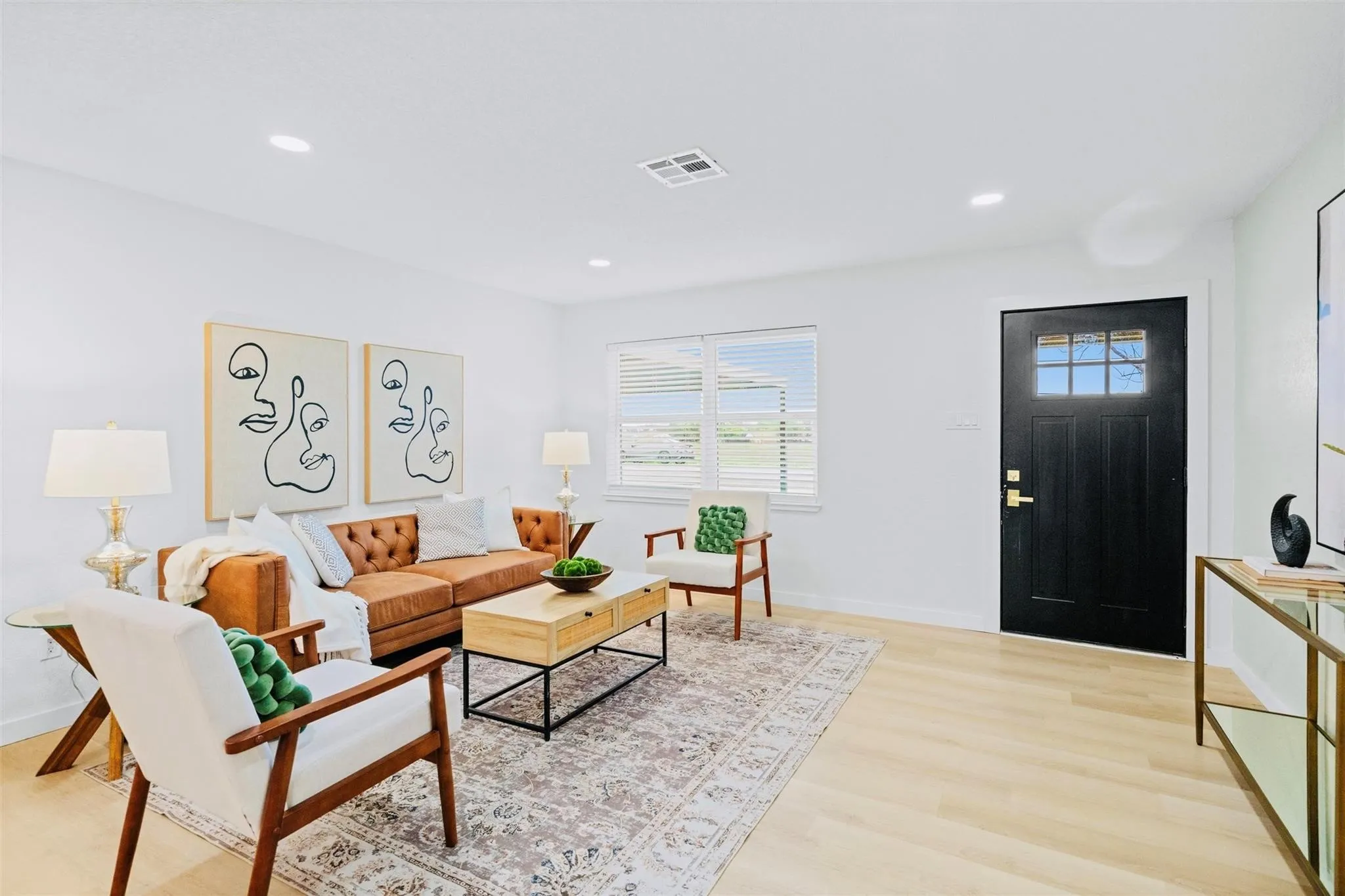 Recessed ceiling lighting, light wood-finish flooring, white walls, and a black paneled entry door with glass inserts
