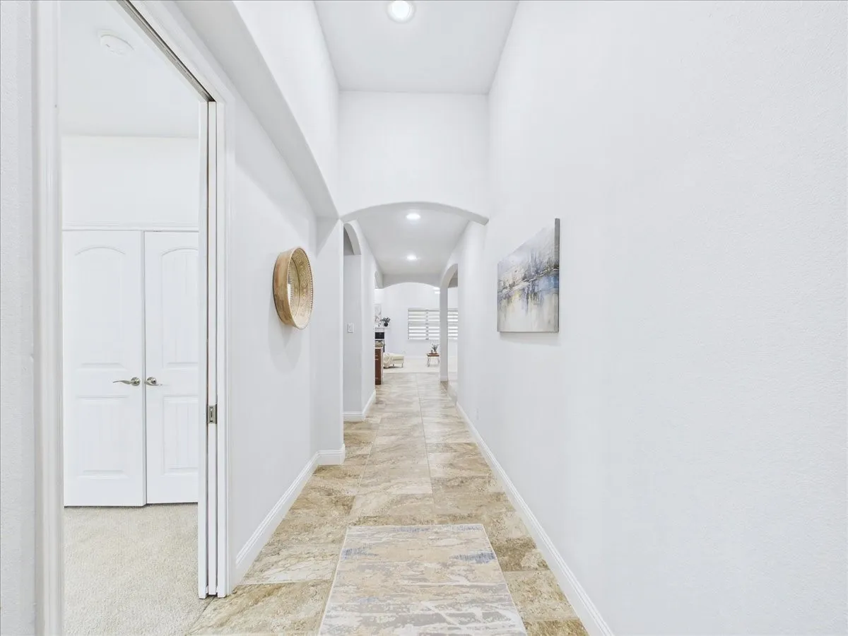 Hallway featuring arched entryways, recessed lighting, and tile flooring