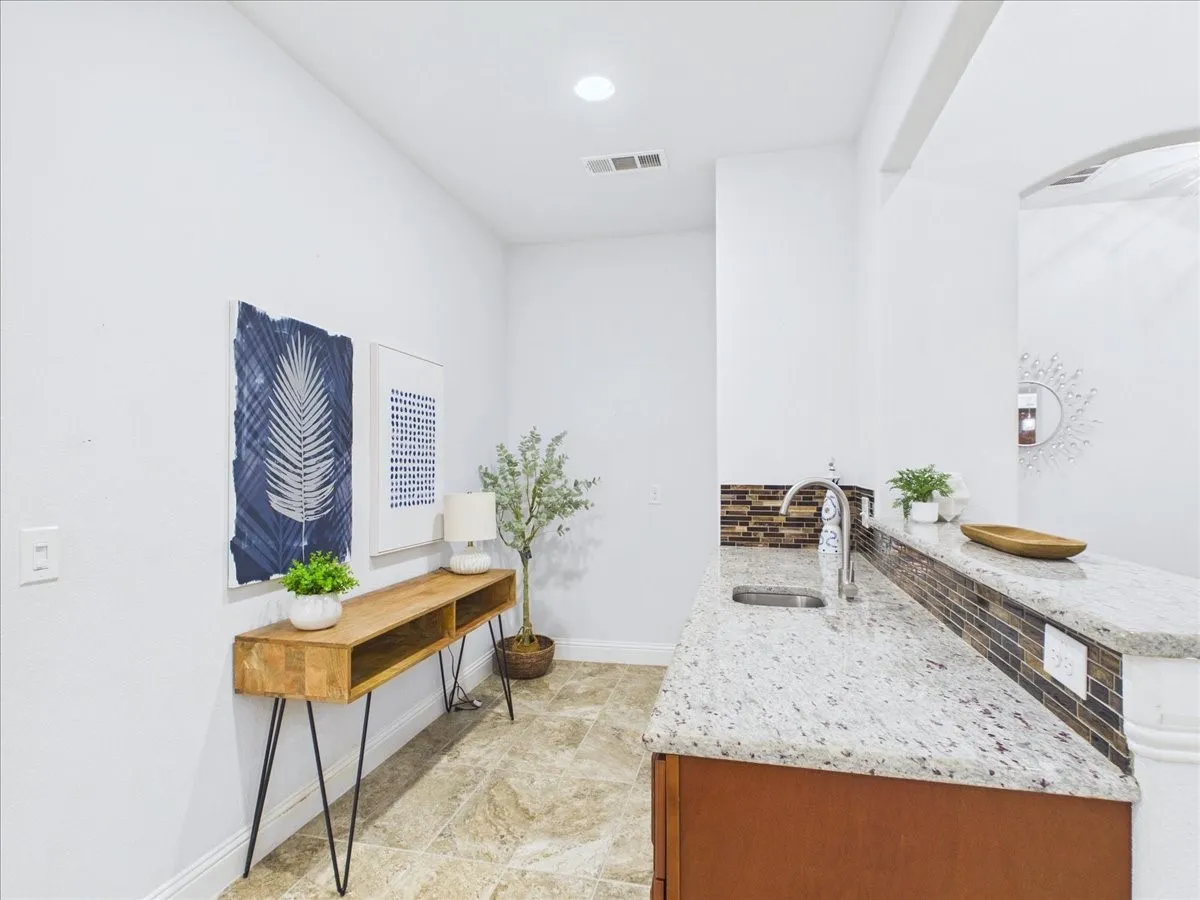 Granite-finish countertops, undermount sink with gooseneck faucet, tiled backsplash, and recessed lighting