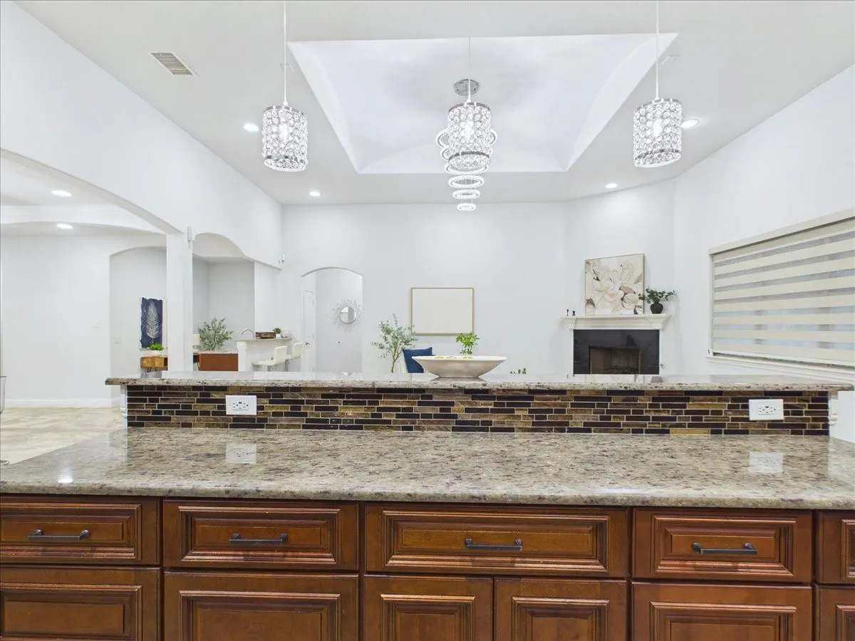 Kitchen island featuring granite countertops, a mosaic tile backsplash, and rich wood cabinetry