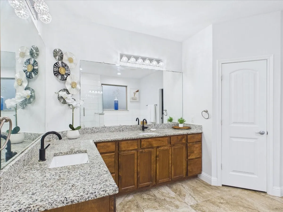 Dual vanity with granite countertops, undermount sinks, and matte black fixtures