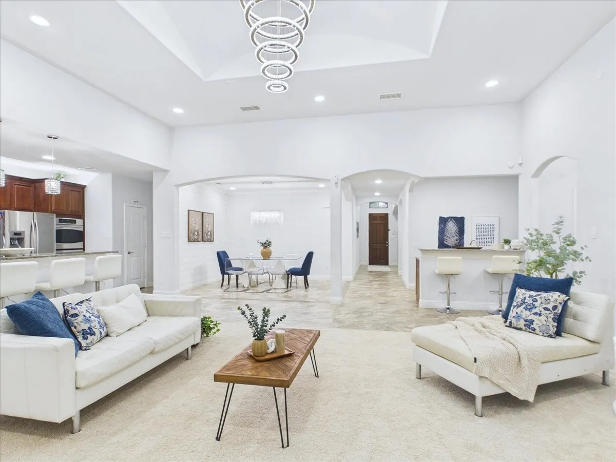 Open-concept living space featuring expansive light-filled interiors with coffered ceiling details, recessed lighting, and neutral finishes throughout