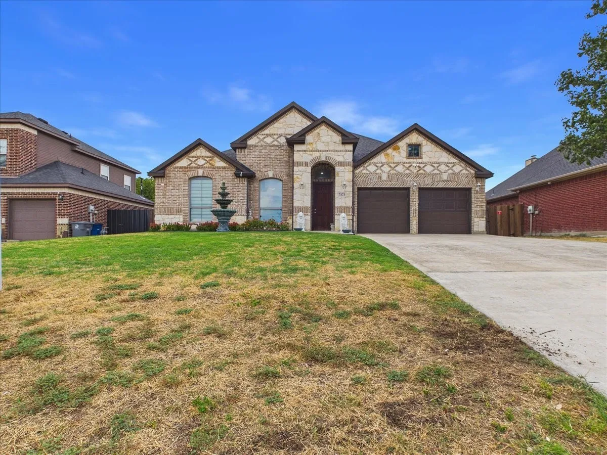 Brick and stone exterior with arched windows, a two-car garage, and a tiered fountain