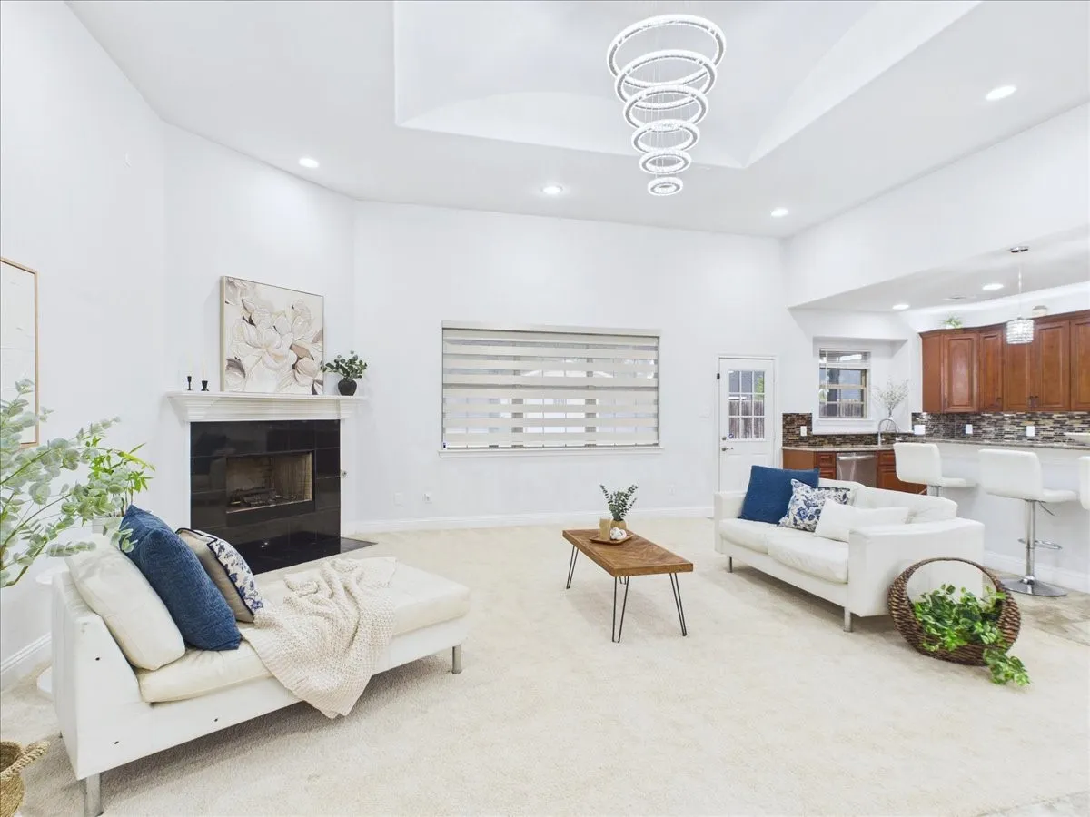 Recessed lighting, fireplace with a dark surround, kitchen with wood cabinetry and a tile backsplash, and a decorative chandelier