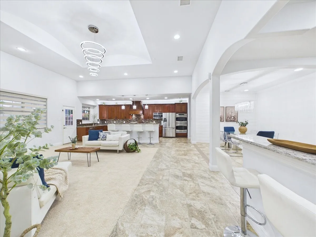 Recessed lighting, arched doorways, tray ceiling, kitchen island with seating, and wood-finish cabinetry
